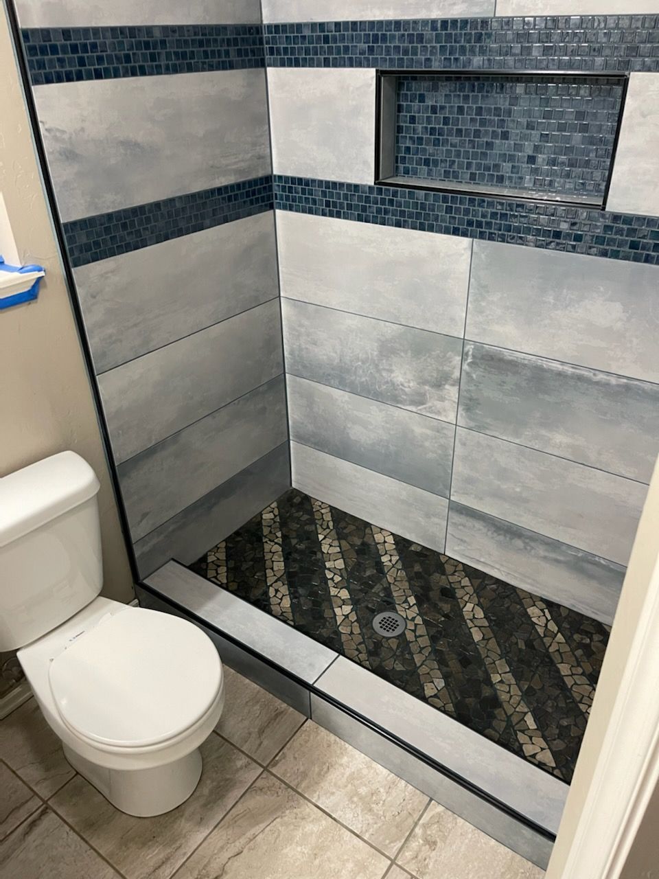 Small tiled bathroom with a toilet and a walk-in shower under construction.