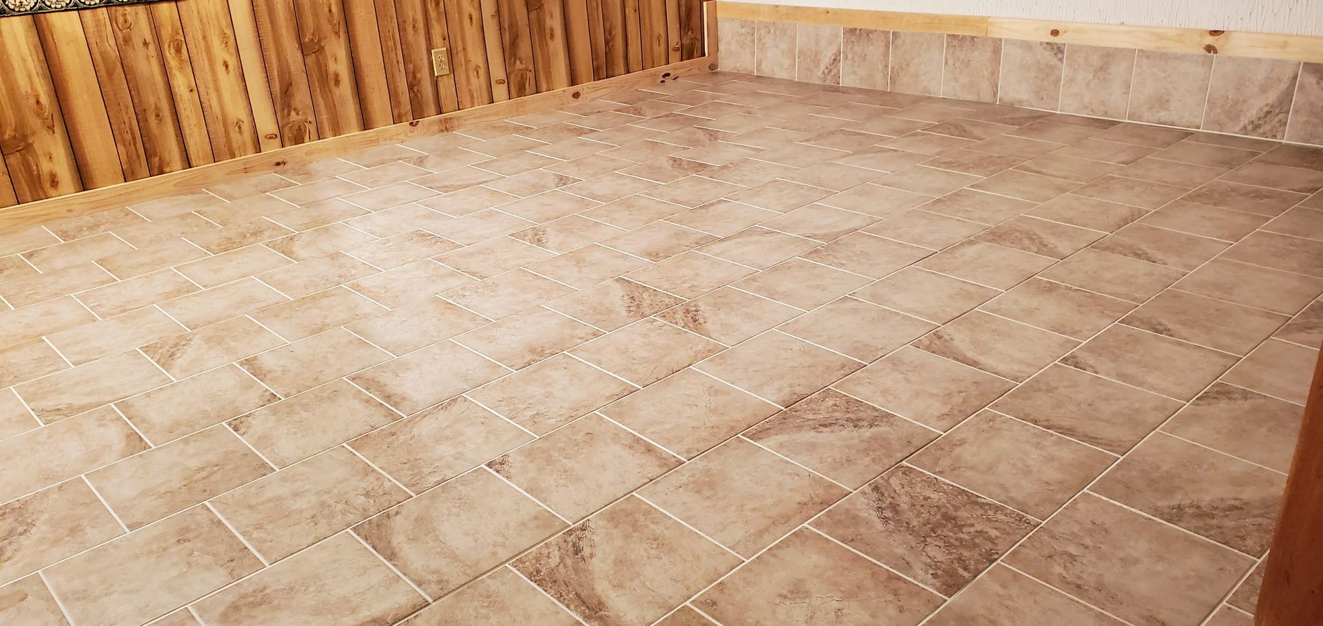 Empty beige tiled floor with wooden walls along the sides and back corner