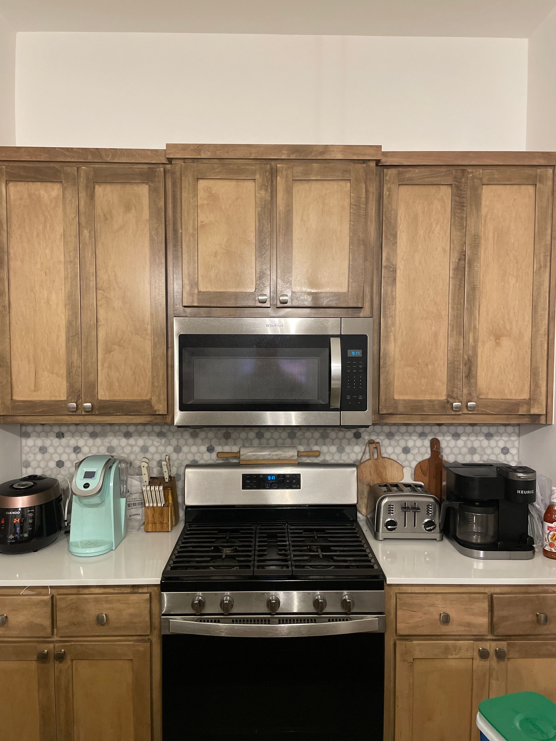 Kitchen with wooden cabinets, stainless steel stove, microwave, and mint-green appliances on the counter.