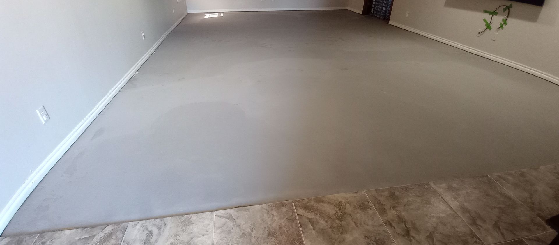 Empty beige carpeted room with white walls and a tiled floor edge in the foreground
