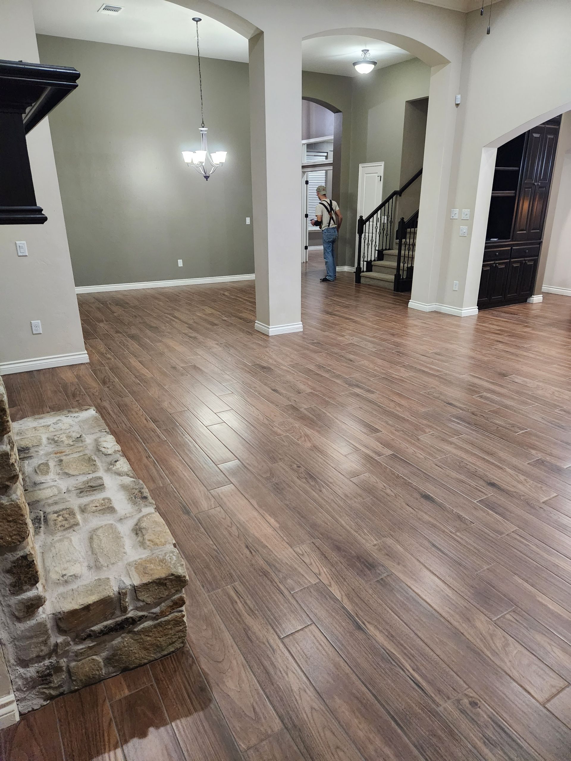 Empty home interior with wood floors, stone accent wall, white columns, and arched entryways.