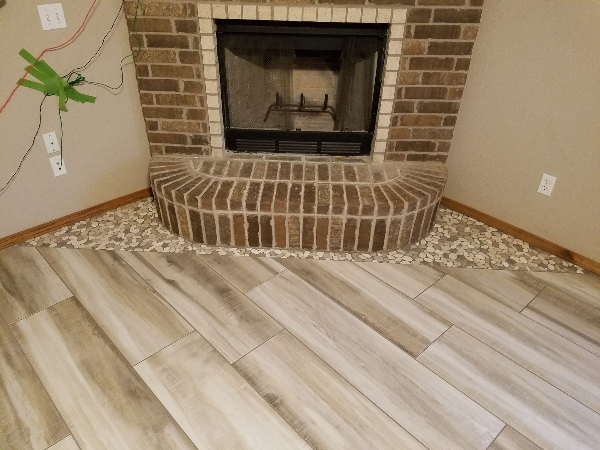 Brick fireplace with tiled hearth in a room with light wood flooring and tan walls