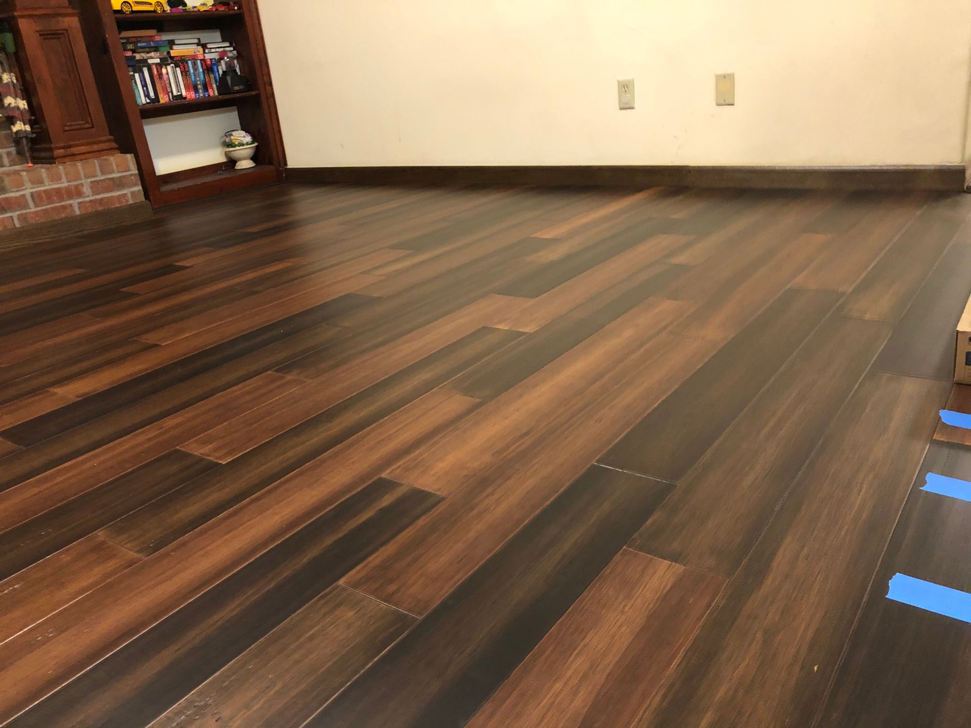 Empty room with dark wood flooring and a bookshelf against the wall