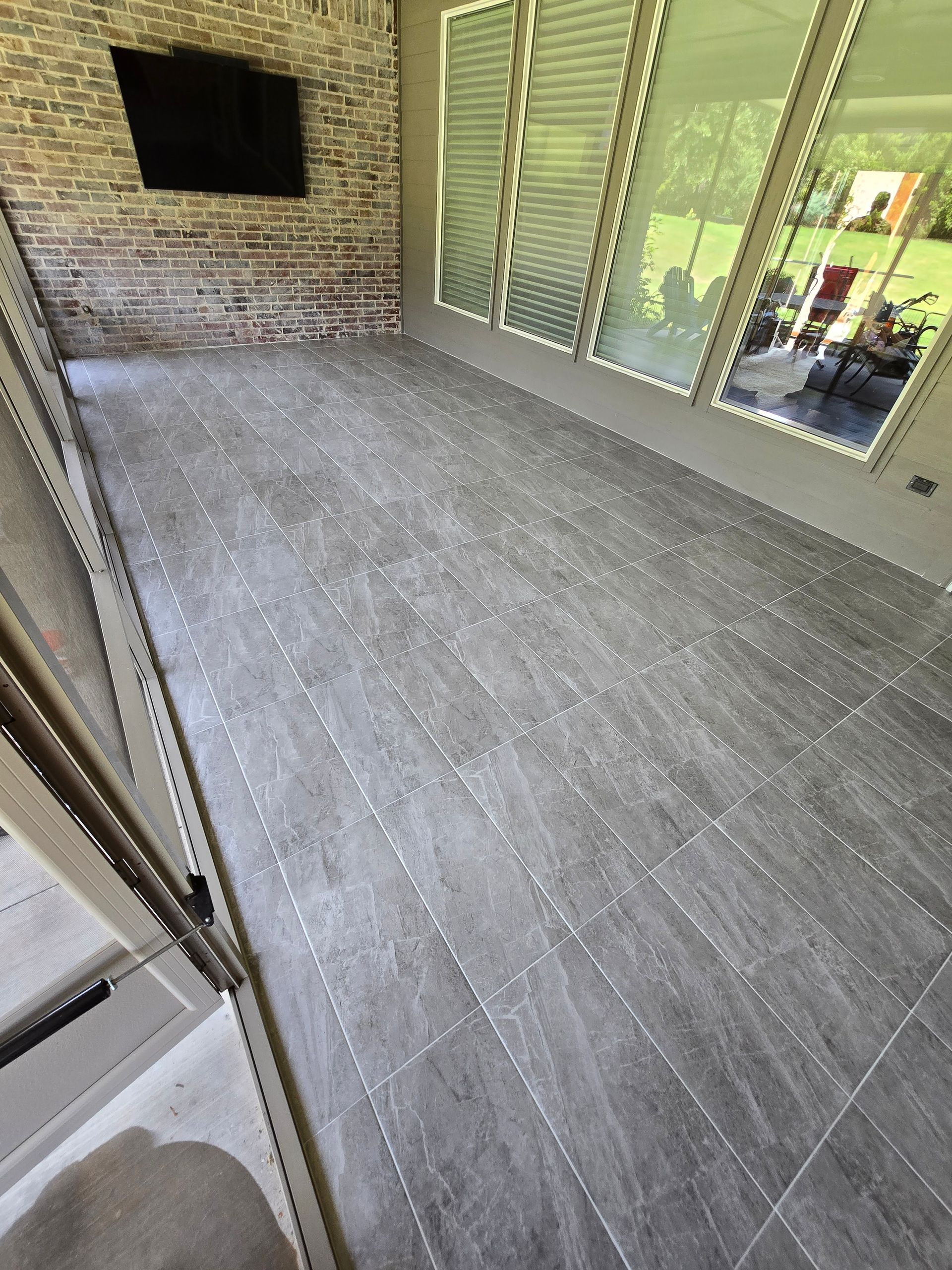 Tiled patio with brick wall, sliding glass doors, and a small window opening to an outdoor seating area
