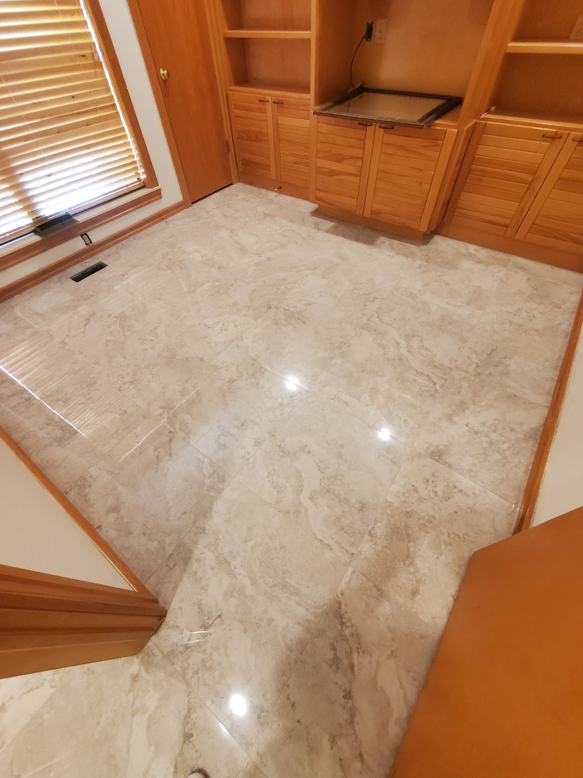 Bright marble floor in a wood-paneled room with cabinets and a window with blinds.
