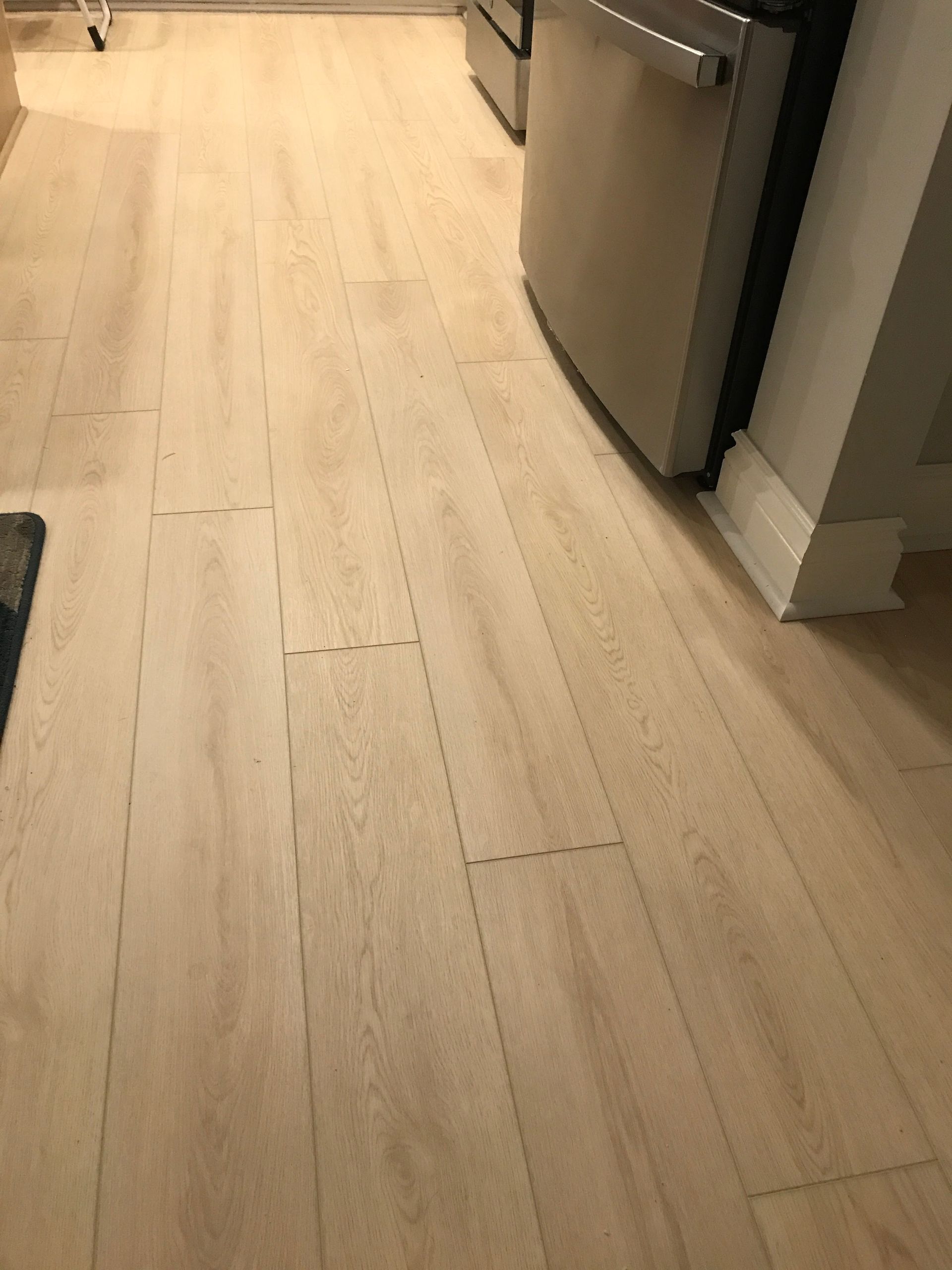 Light wood kitchen floor with a stainless steel appliance and cabinet edge.