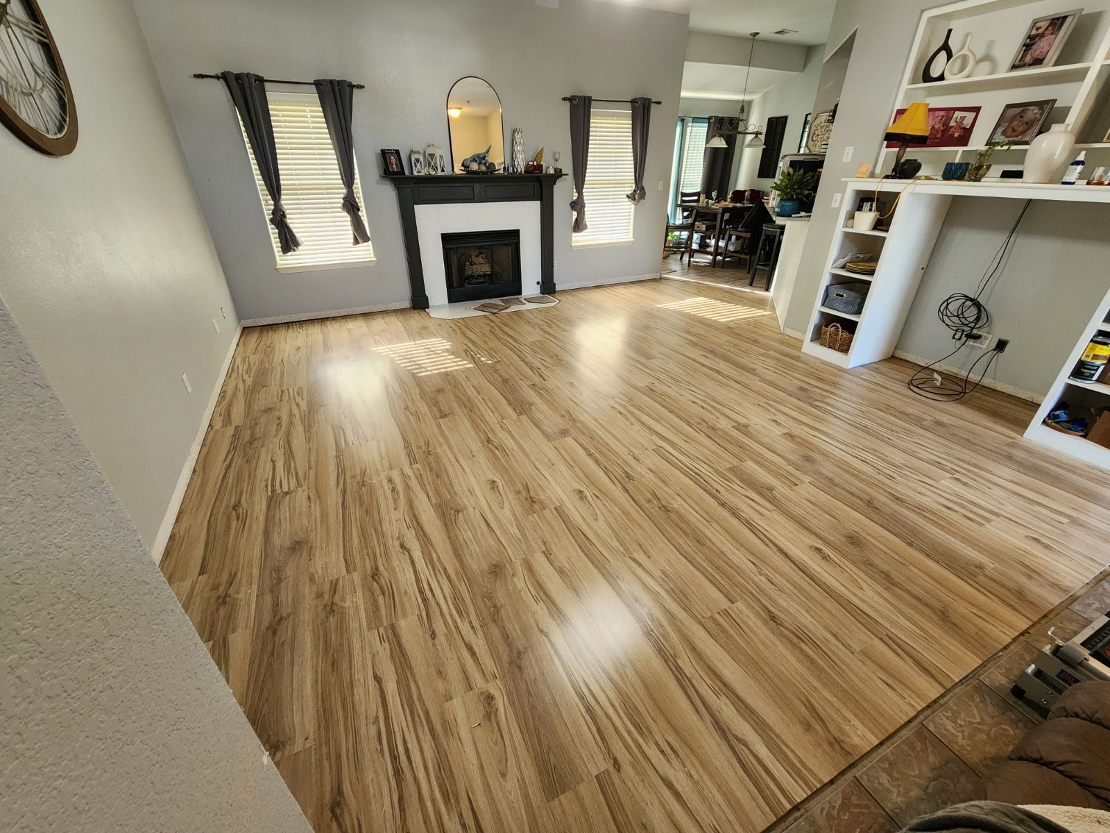 Bright living room with wood floors, fireplace, and built-in shelves, viewed from a wide angle