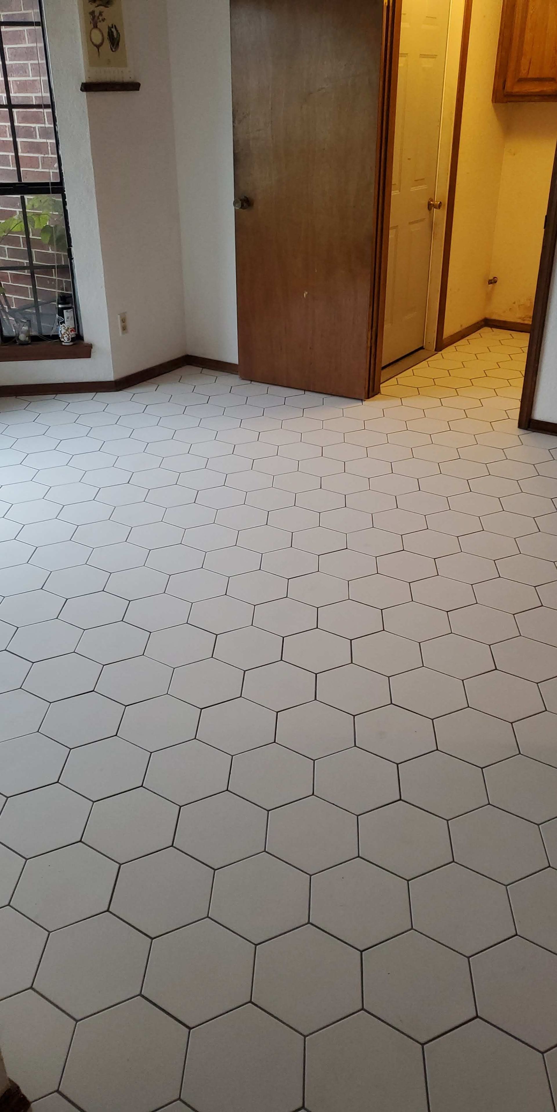 White hexagonal tile floor in a hallway with open wooden doors and warm yellow lighting