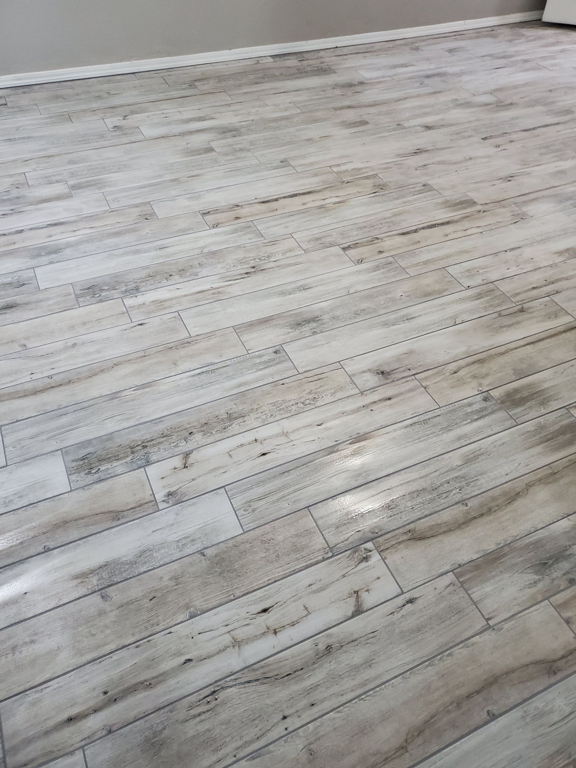 Empty room with light wood plank flooring and a white wall corner