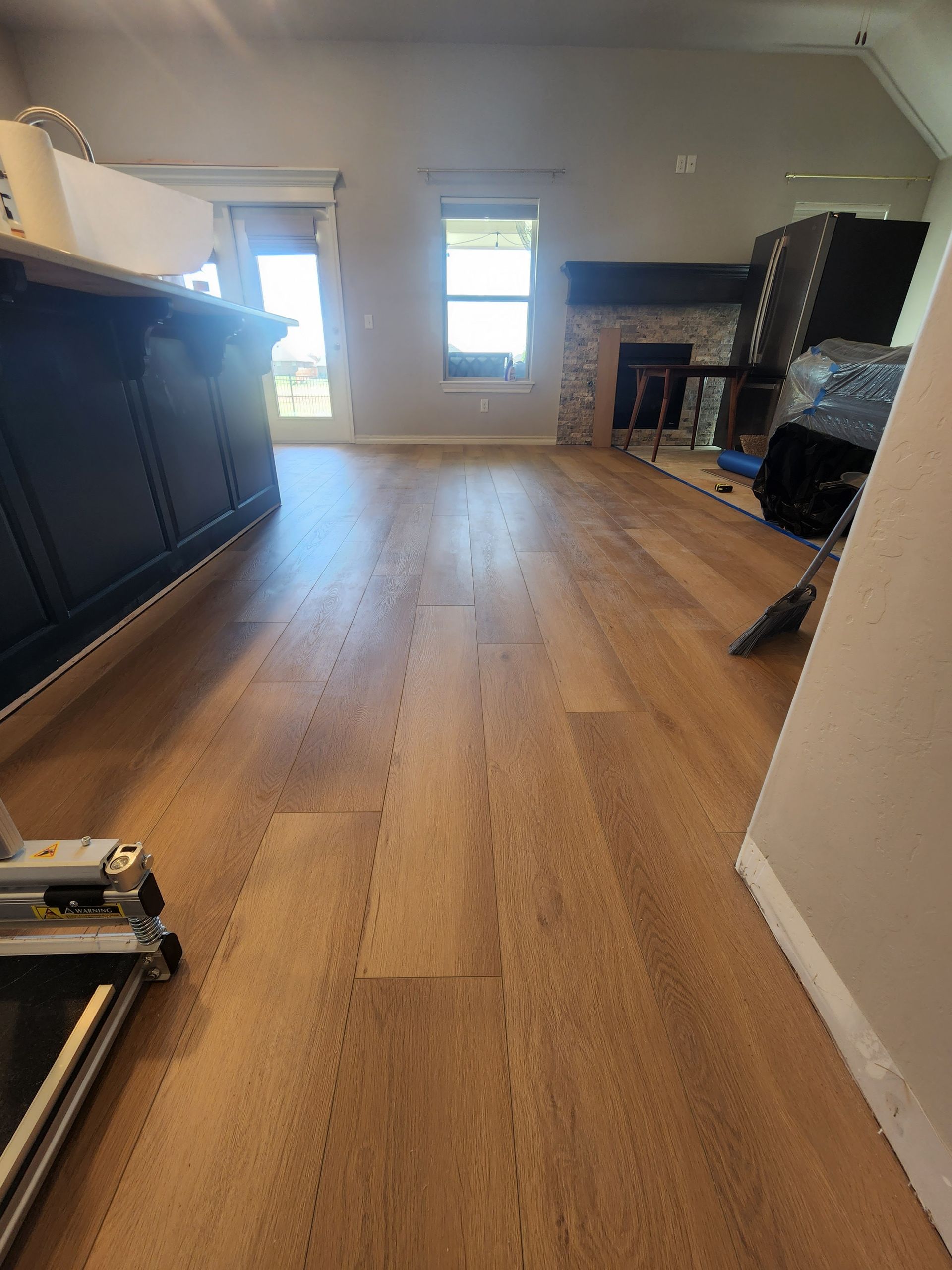 Living room with wood floors, fireplace, windows, and dark TV cabinets along the left wall