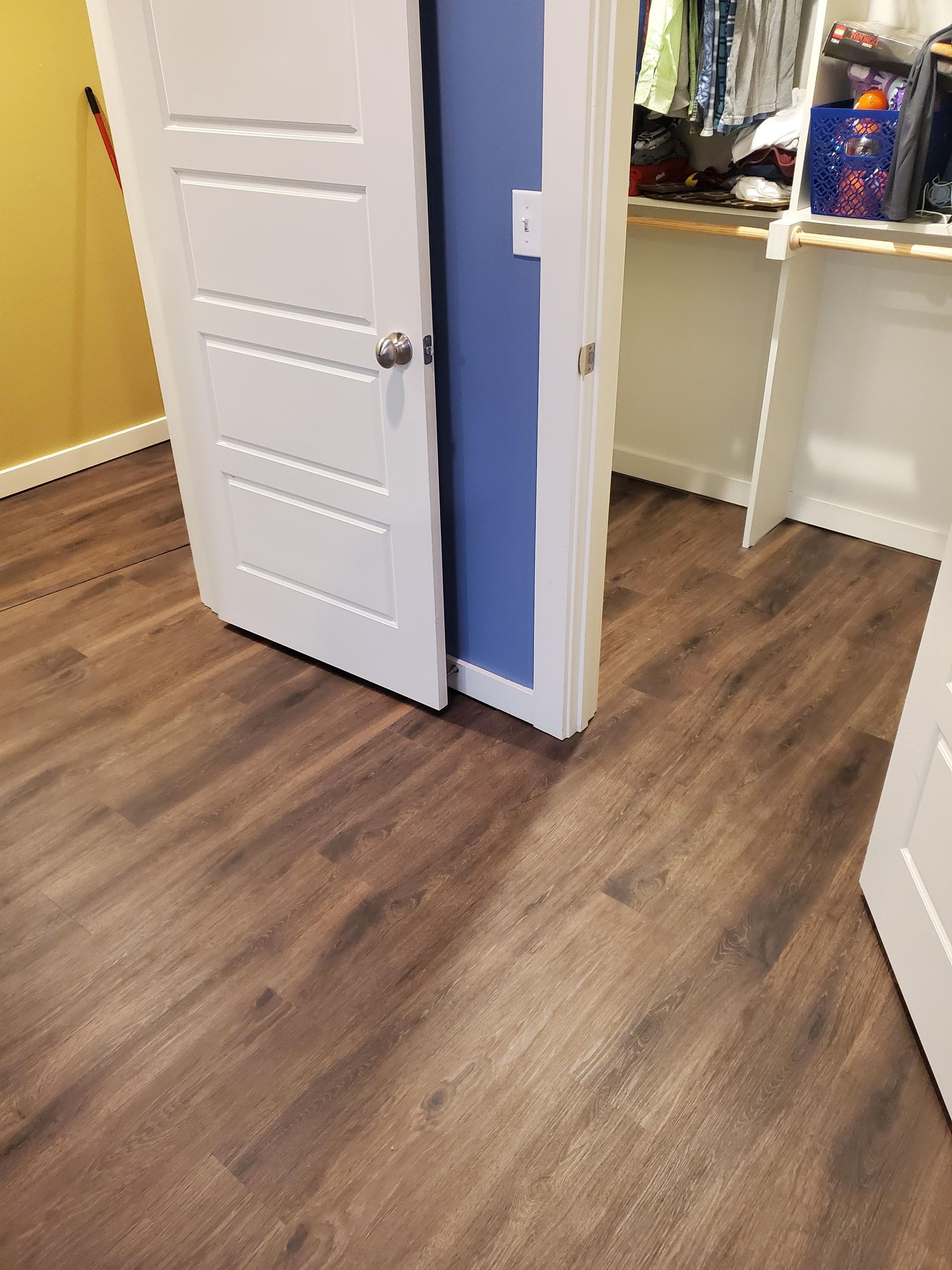 Open closet door in a room with wood flooring and blue accent wall.