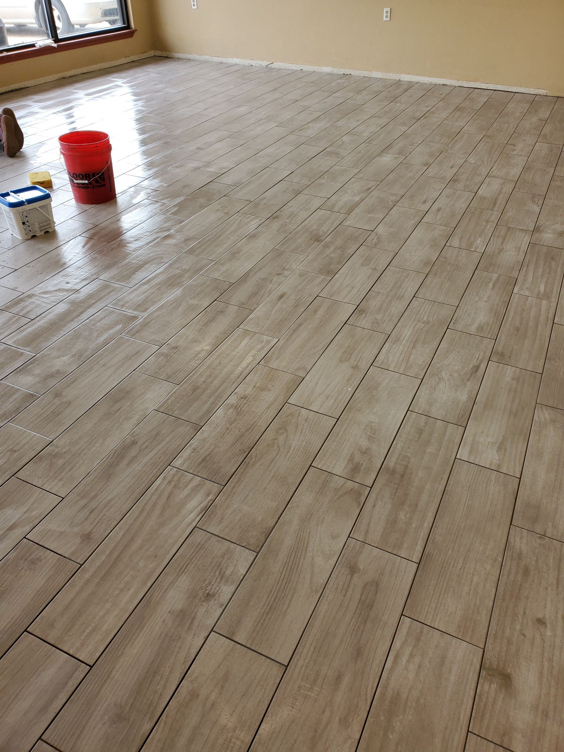 Empty room with light wood-look flooring and a red bucket near the wall