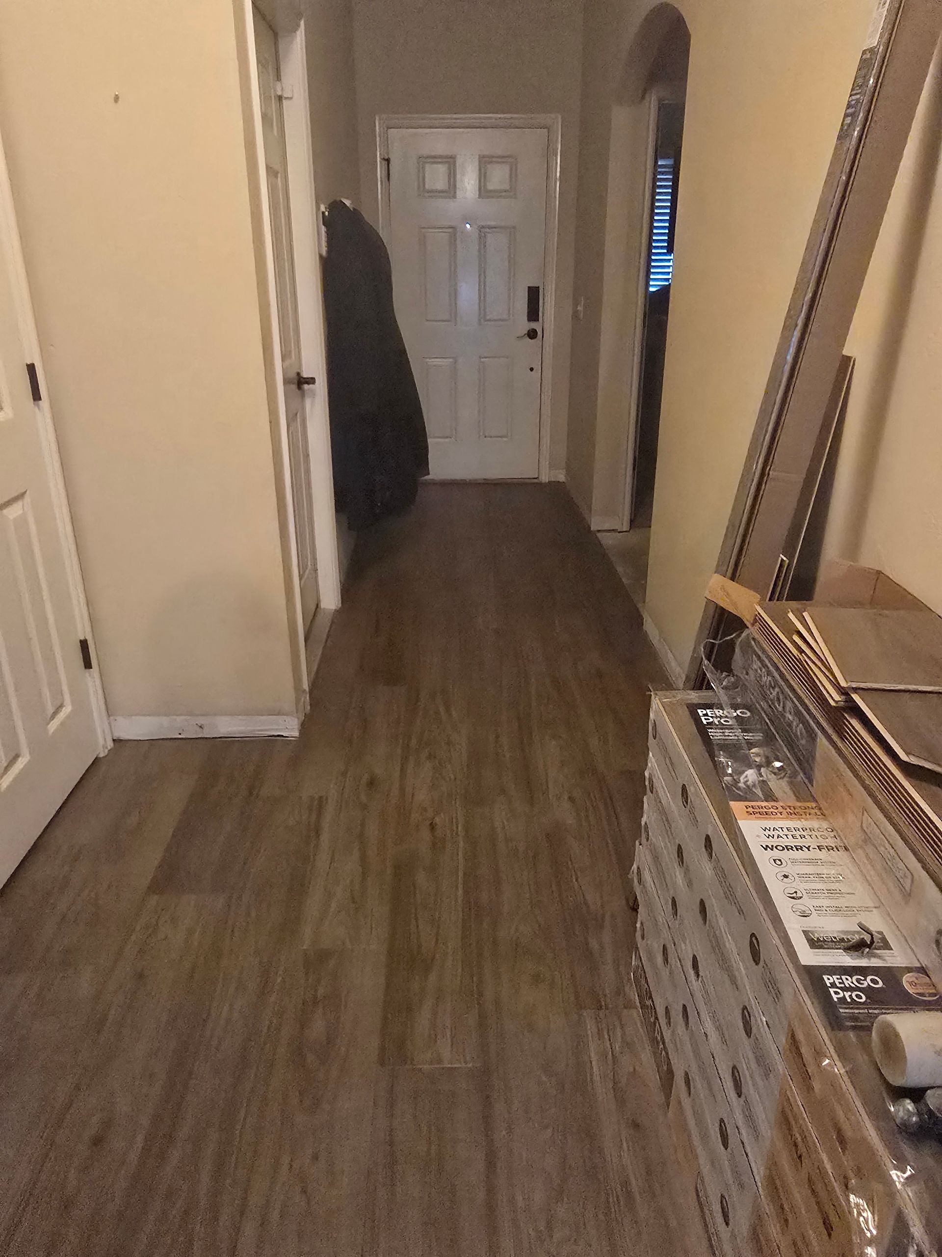 Hallway with wood-look flooring, white doors, and a stack of boxes on the right.