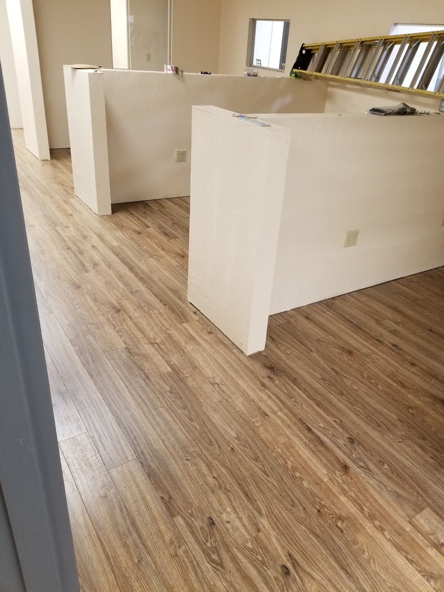 Empty office with white cubicle walls and wood-look flooring