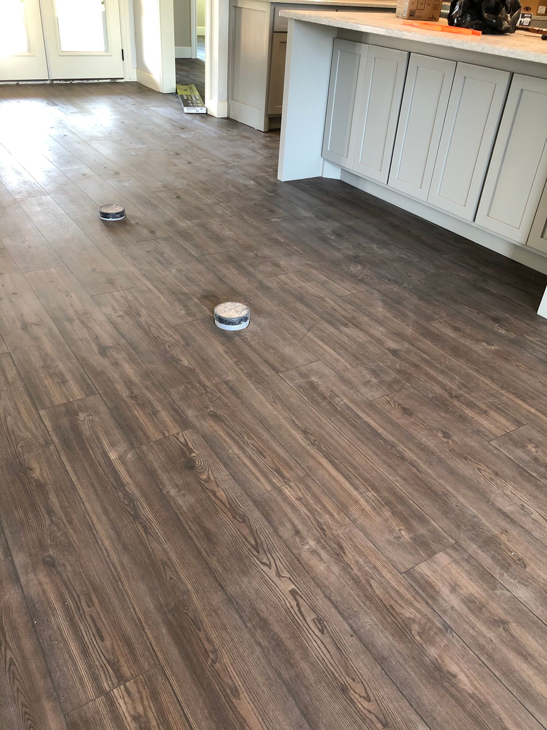 Empty kitchen with wood floor and two small objects near the center.