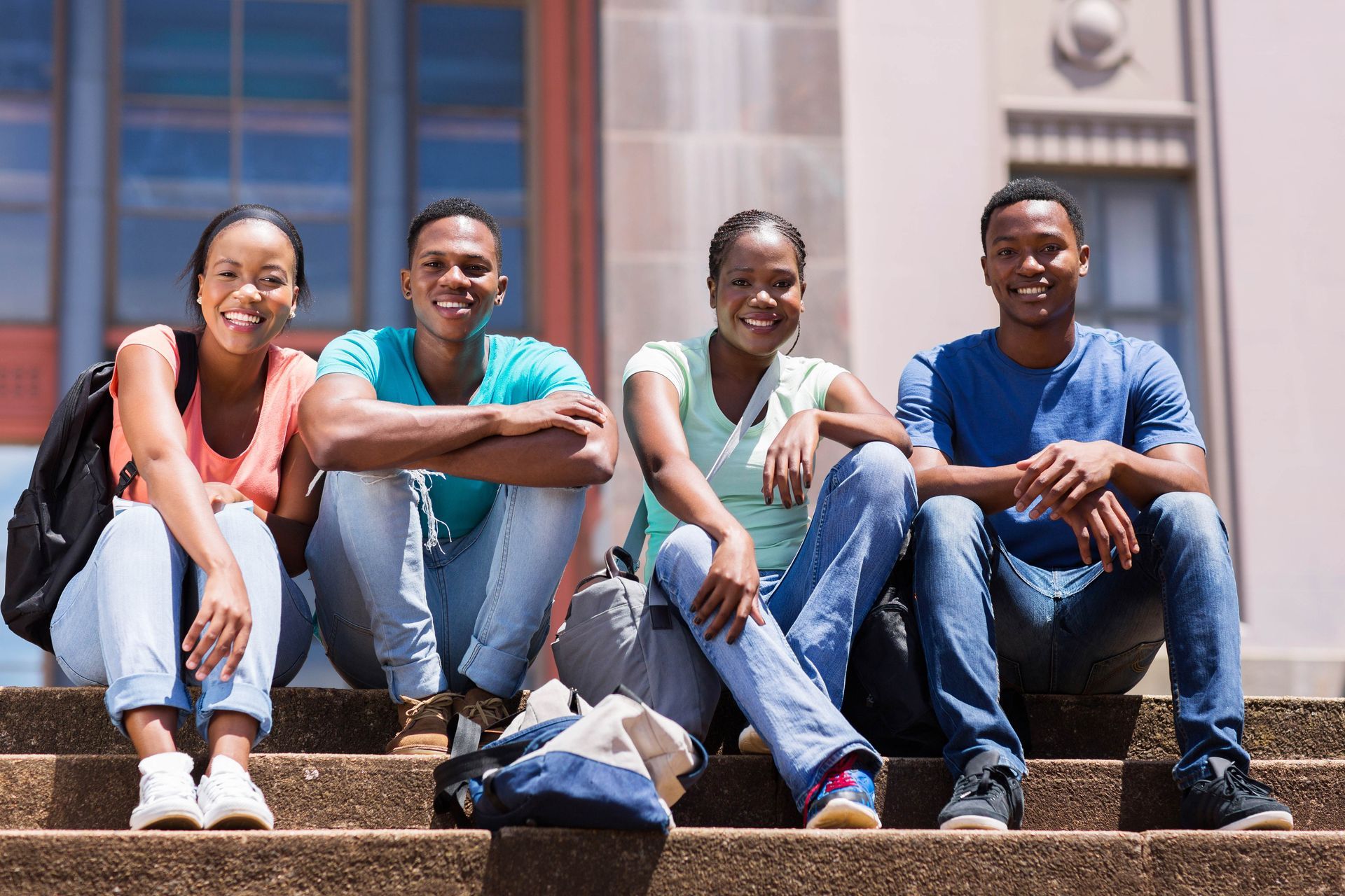 a group of young people are sitting on the steps of a building