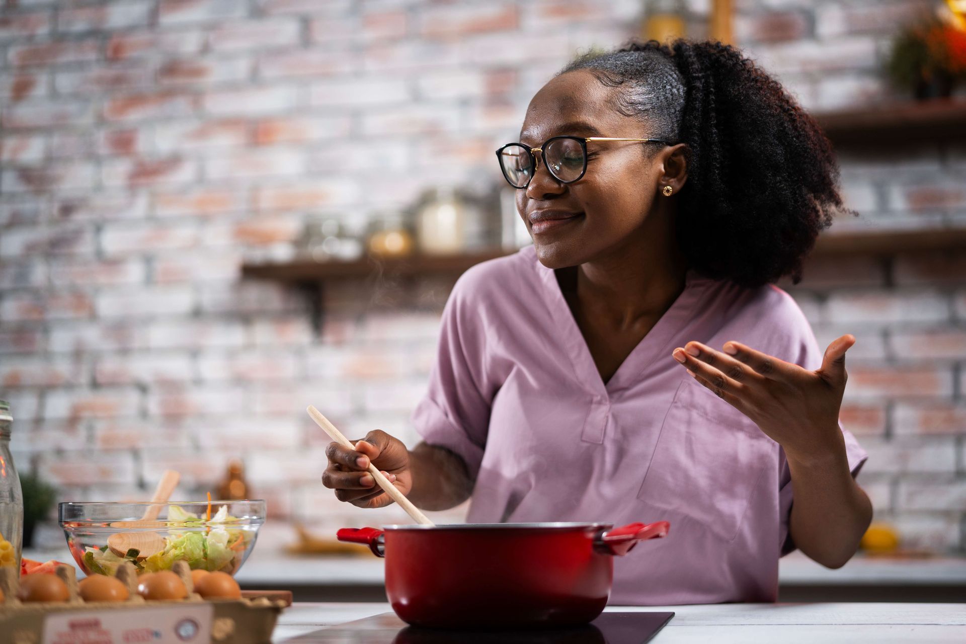 a woman is cooking in a red pot in a kitchen