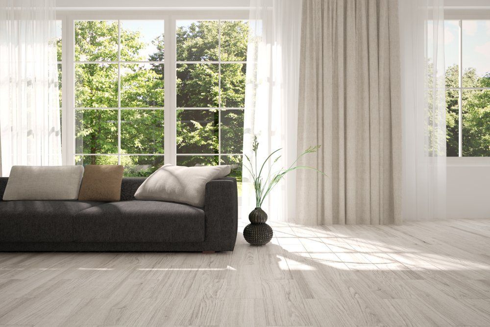 A Living Room with A Black Couch and A Vase of Flowers in Front of A Large Window — Cachia Upholstery in Nabiac, NSW