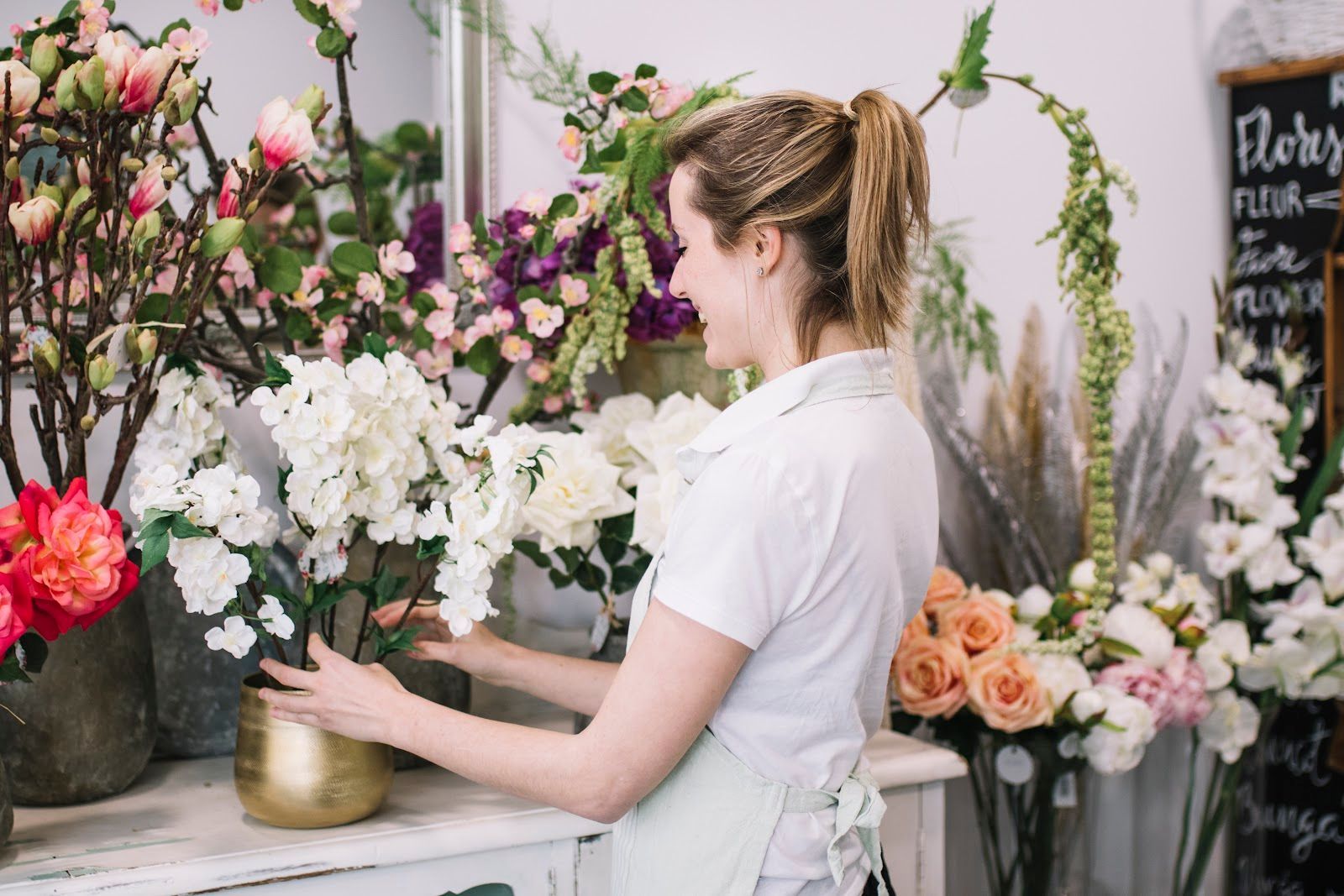 Florist arranging white flowers in a shop surrounded by colorful bouquets