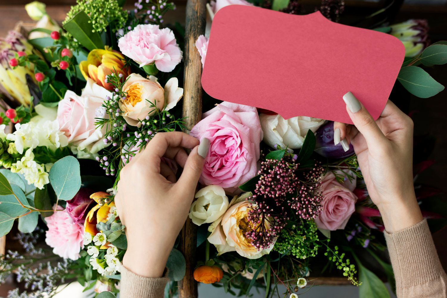 A woman is holding a red card over a bouquet of flowers.