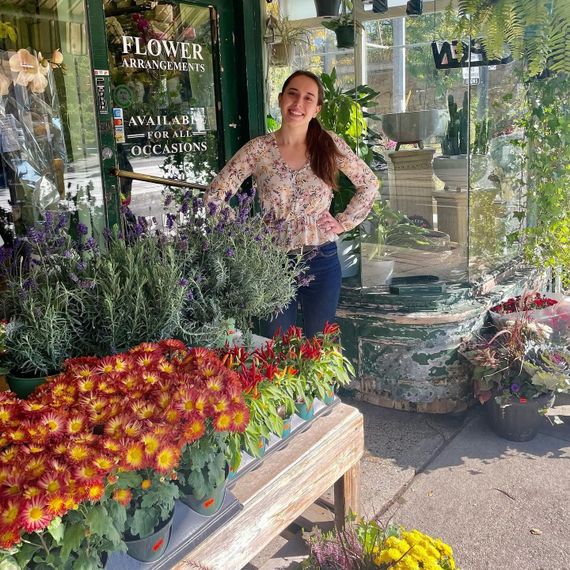 a woman stands in front of a flower arrangements store