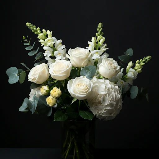 a white vase filled with white flowers and green stems