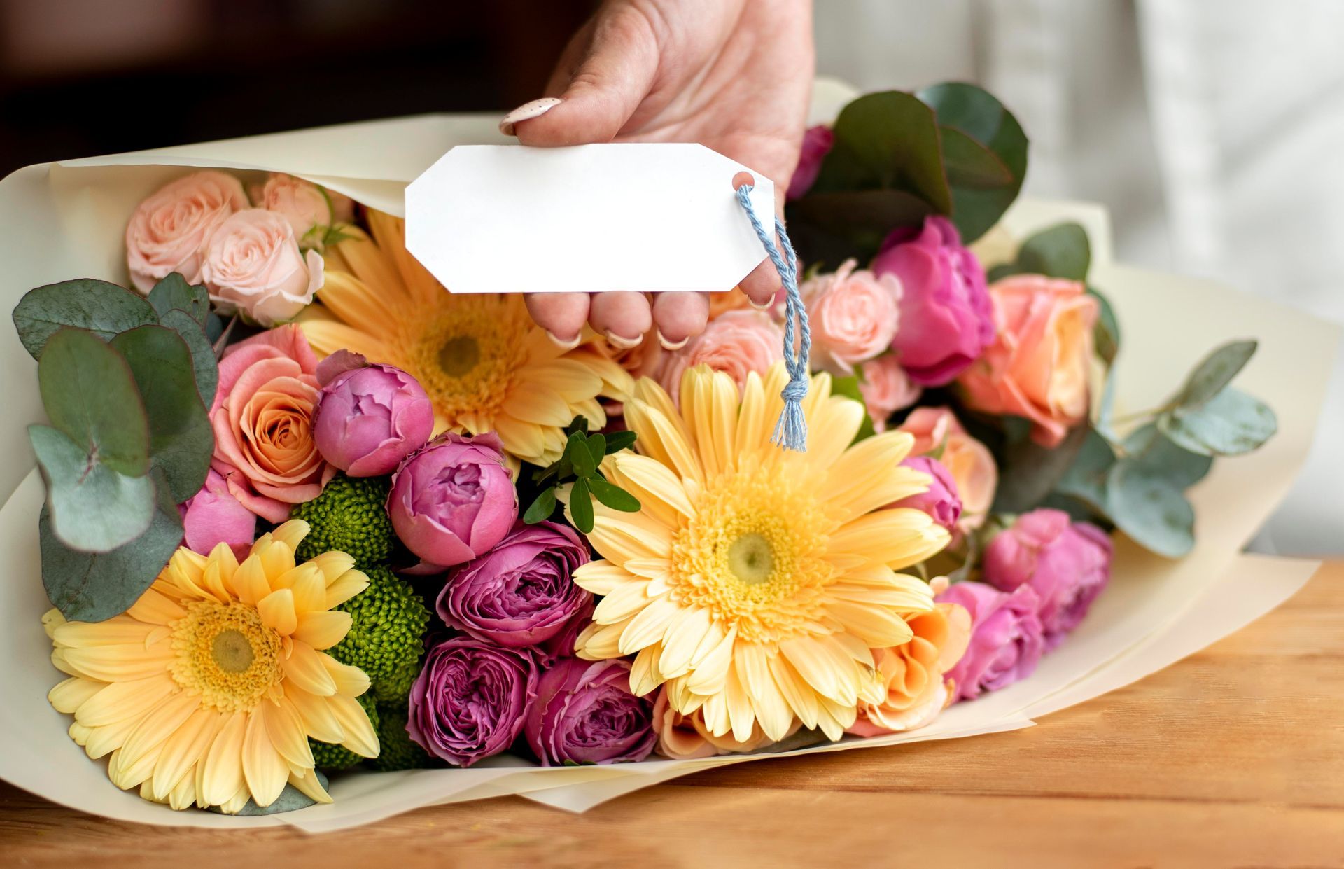 a person holding a tag over a bouquet of flowers