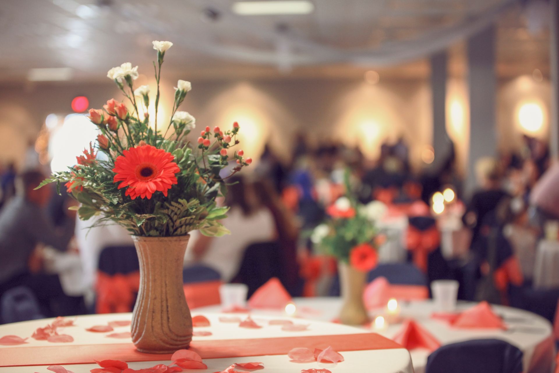 A vase of flowers is on a table at a wedding reception.