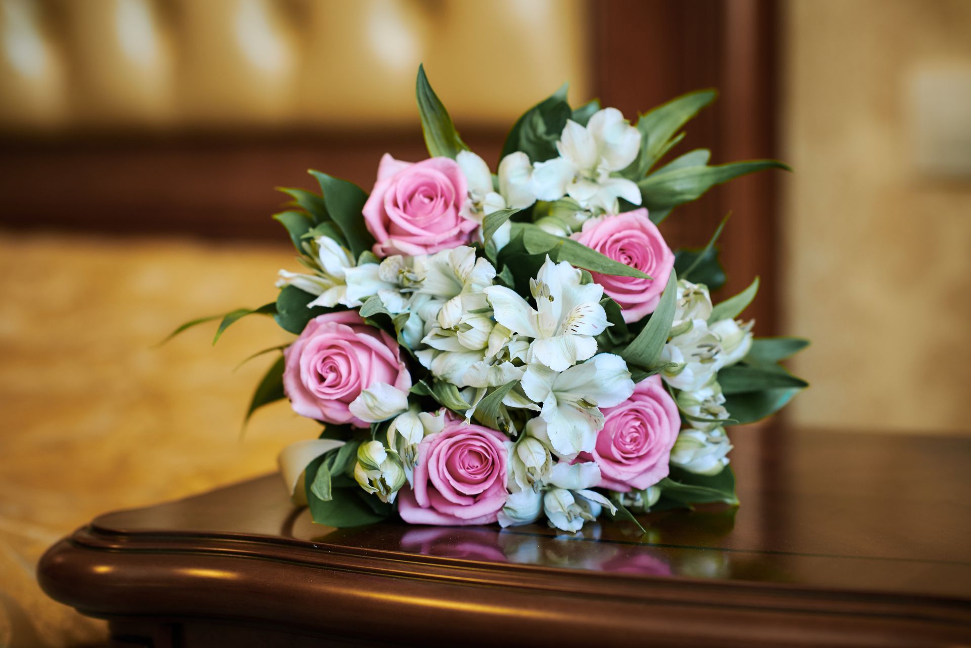 Bouquet of pink roses and white flowers on a wooden table.