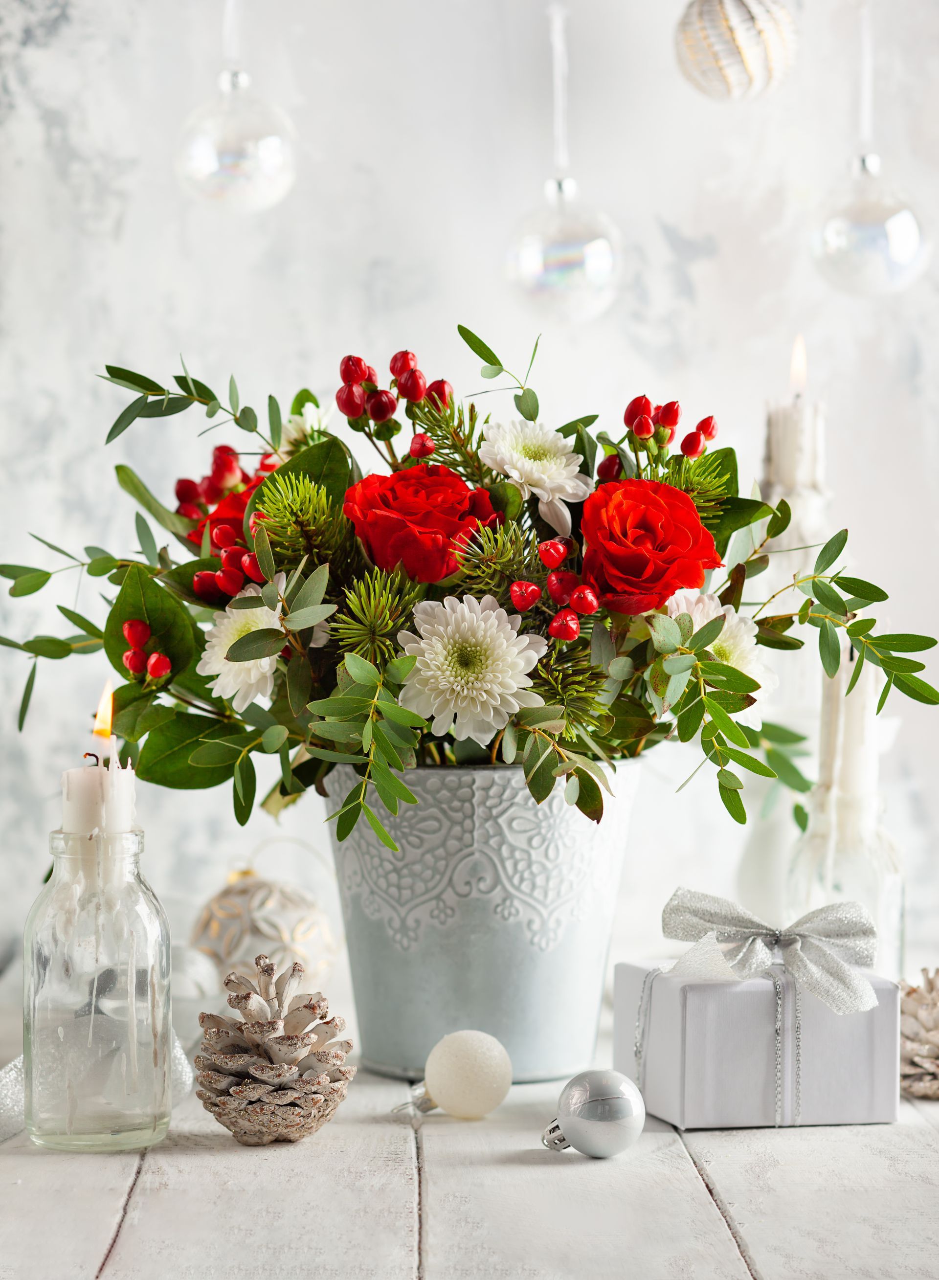 a white vase filled with red and white flowers