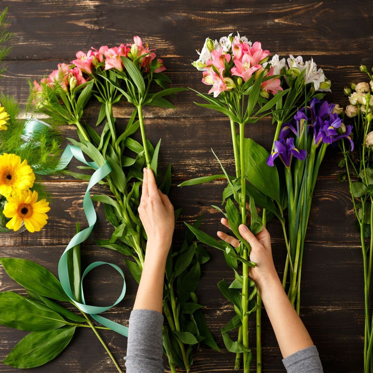 a person is arranging flowers on a wooden table