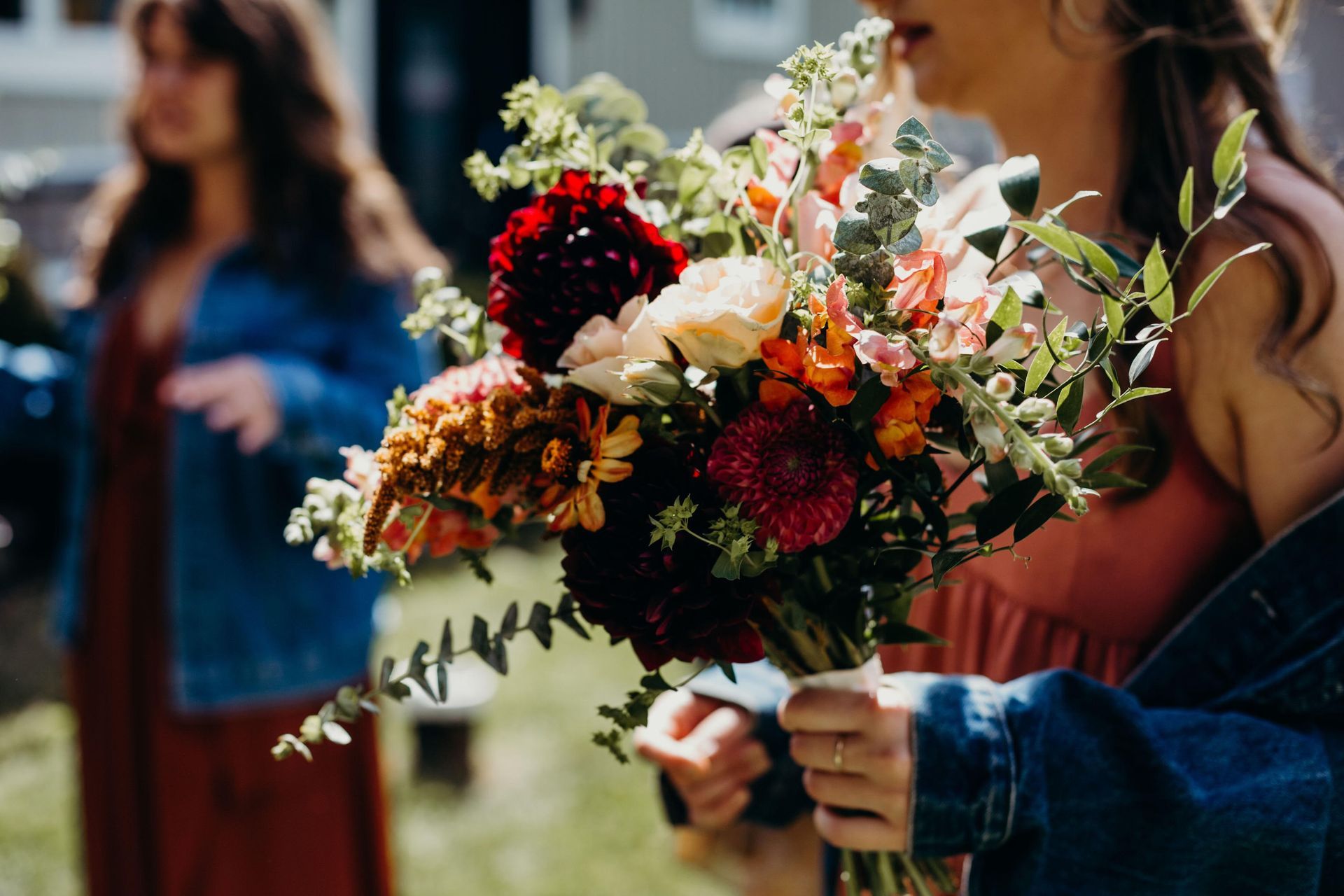 a woman in a denim jacket is holding a bouquet of flowers