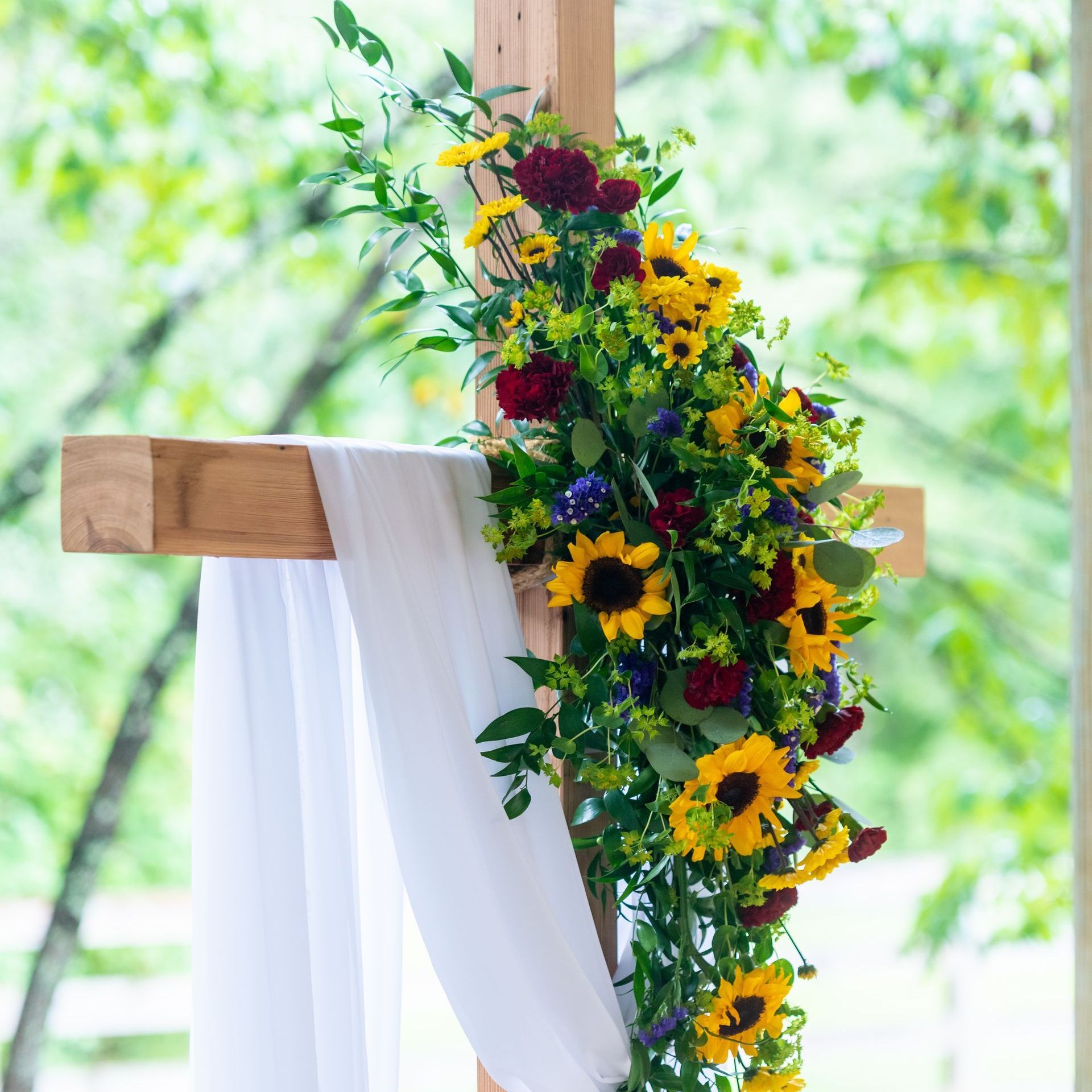 a wooden cross decorated with sunflowers and purple flowers