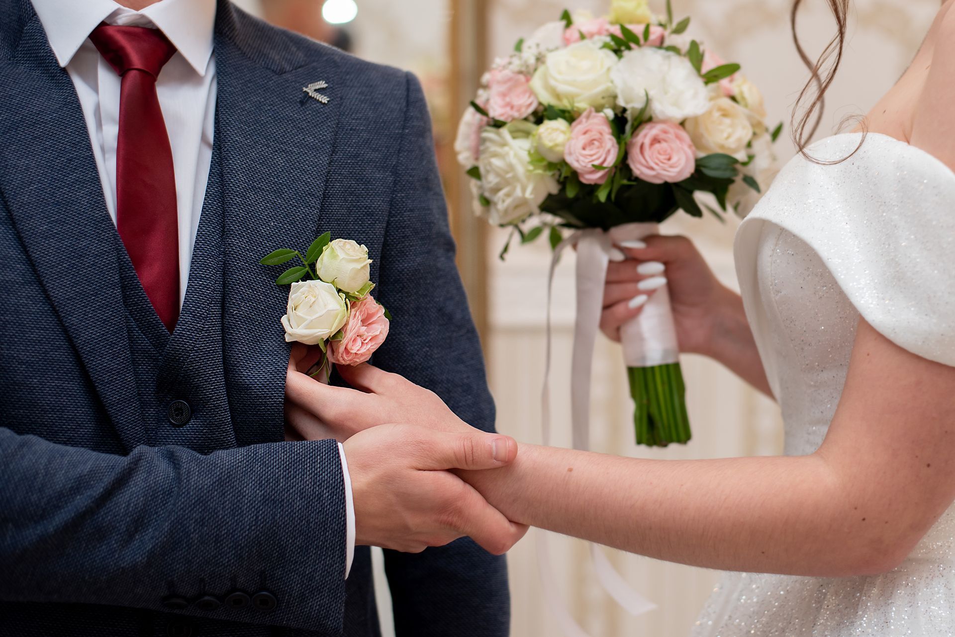 Wedding ceremony: Couple holding hands, bride holding bouquet, groom in blue suit.
