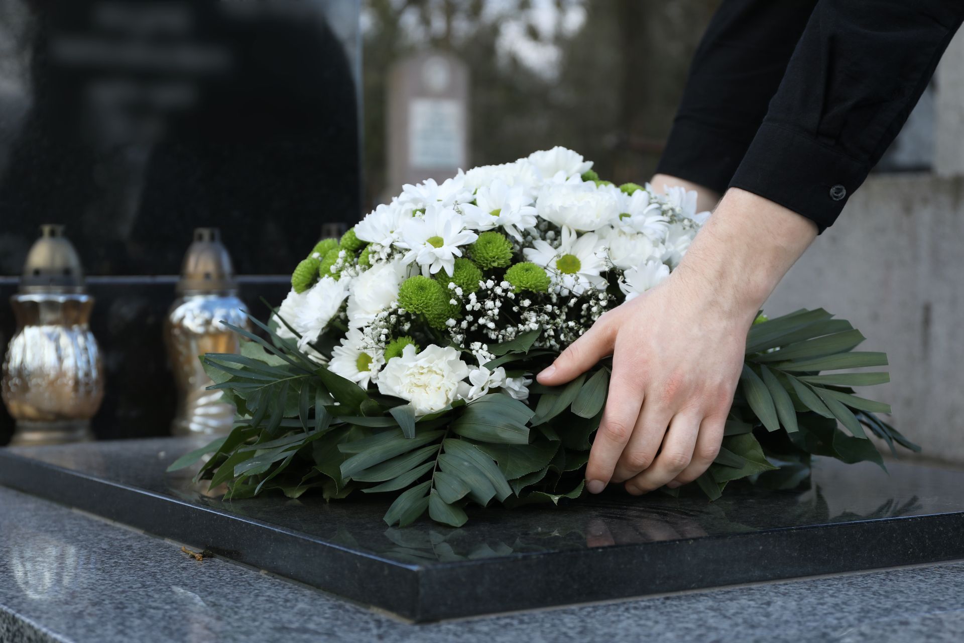 A person is putting flowers on a grave.