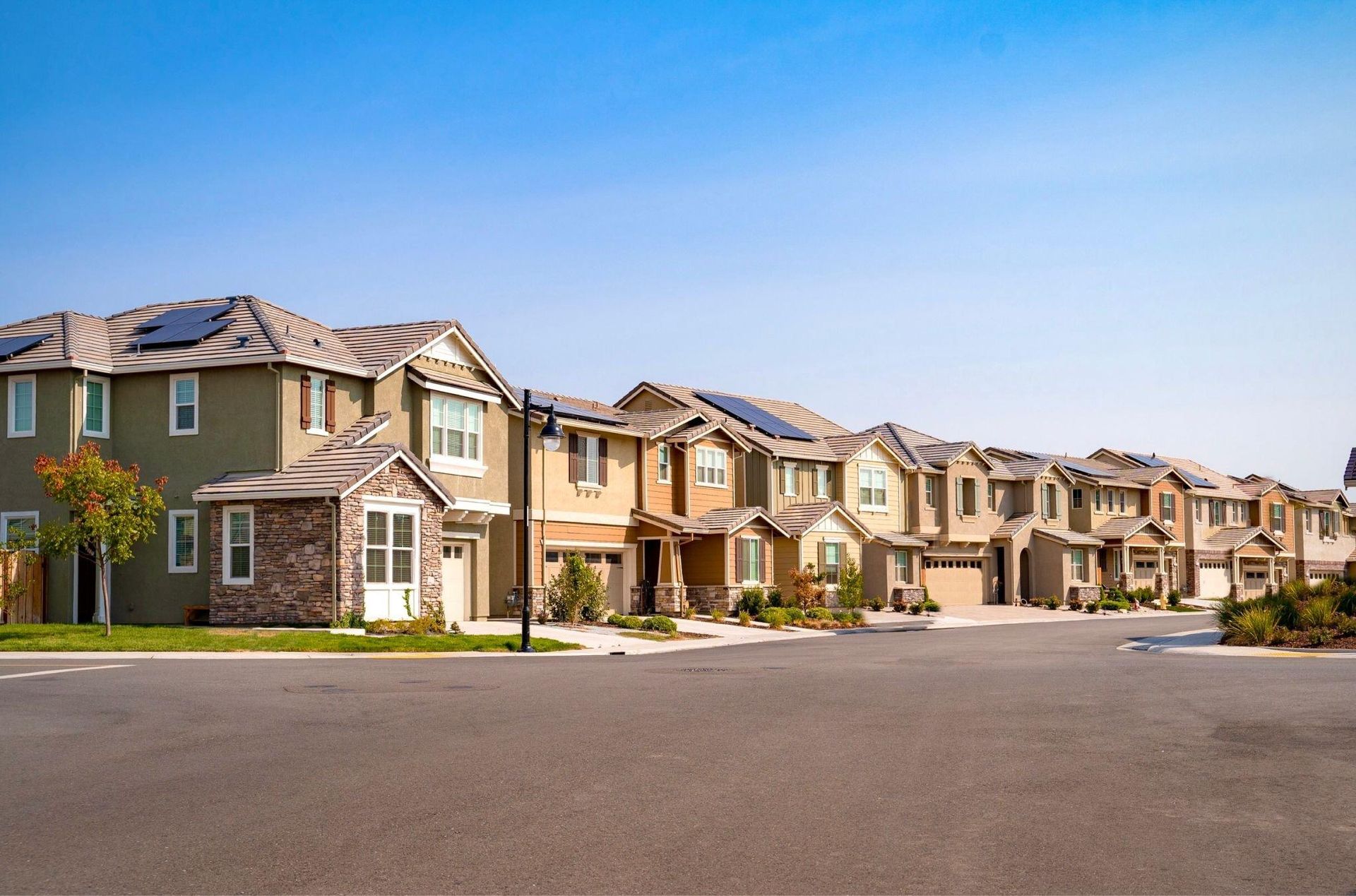 A row of houses in a residential area with solar panels on the roofs.