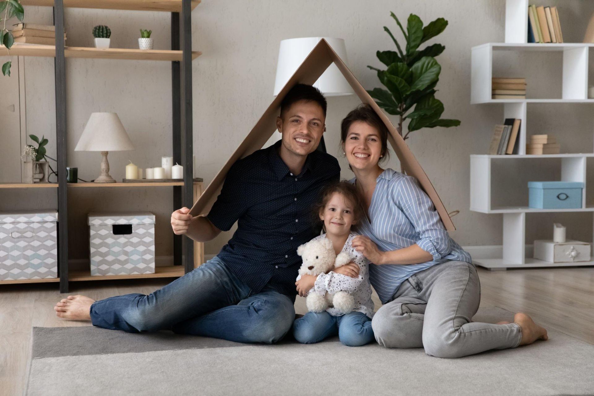 A family is sitting under a cardboard roof in a living room.