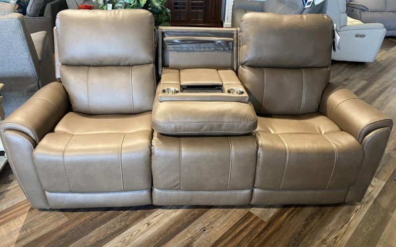 A tan leather recliner couch is sitting on a wooden floor in a living room.