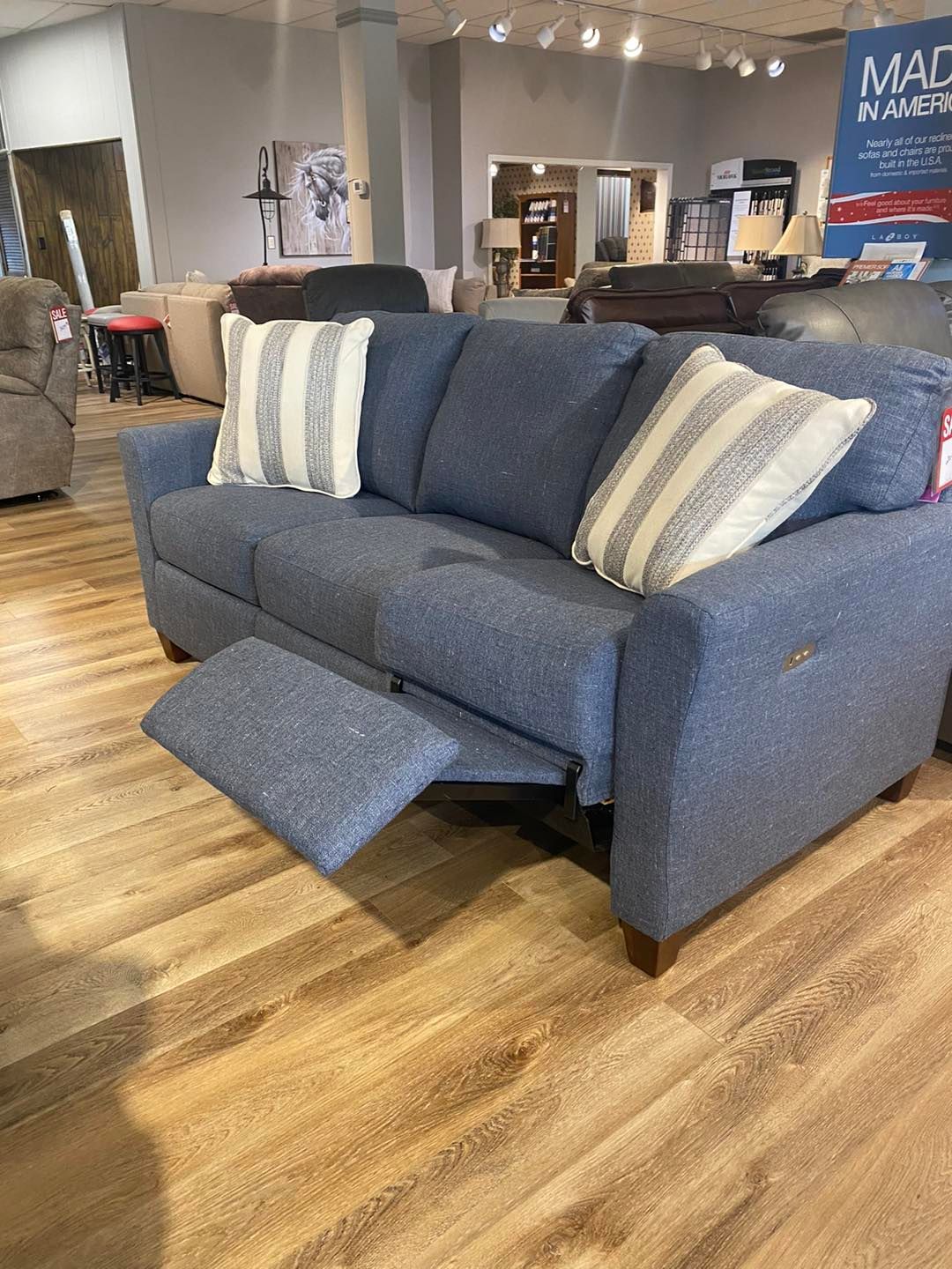 A blue recliner couch is sitting on a wooden floor in a living room.