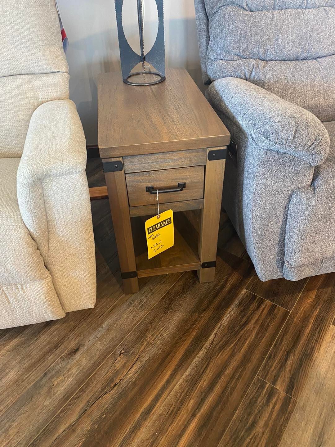 A wooden end table is sitting next to a recliner in a living room.