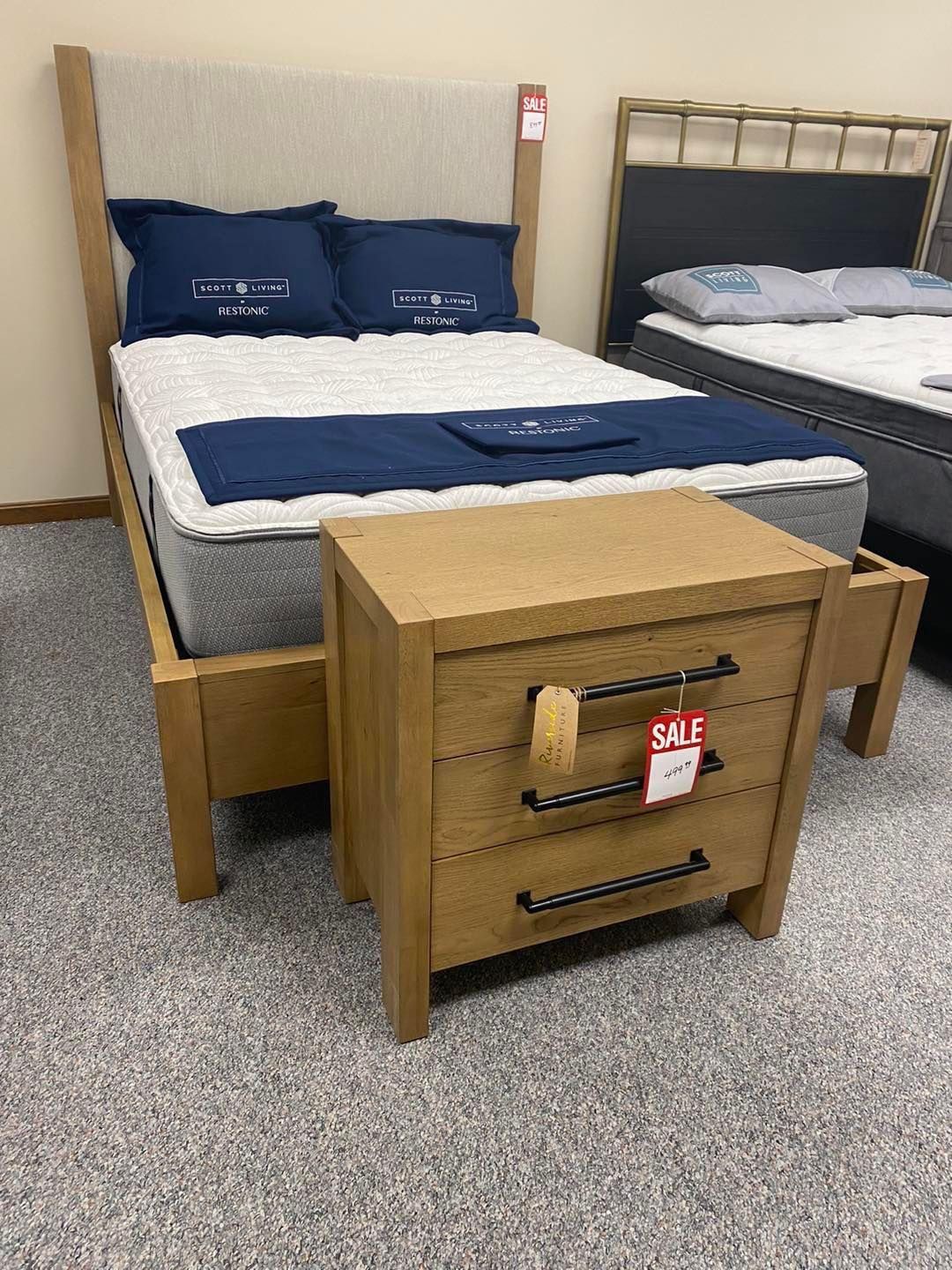 A bed with a mattress and a nightstand in a store.