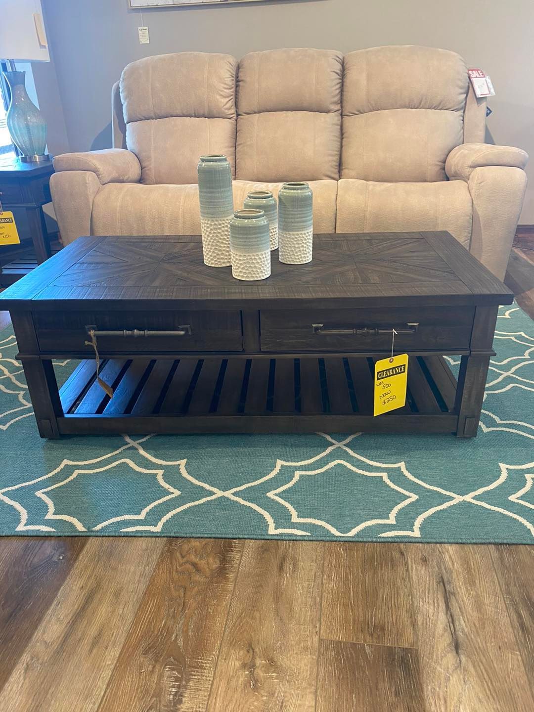 A coffee table is sitting on a rug next to a couch.