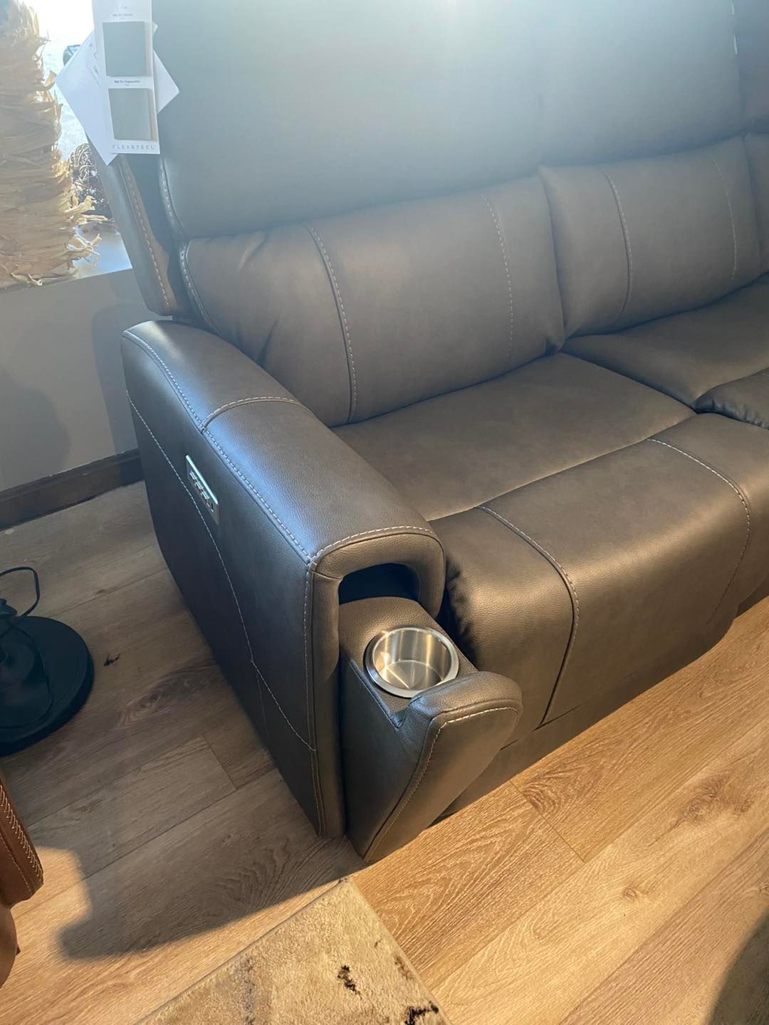 A couch with a cup holder on the arm of it.