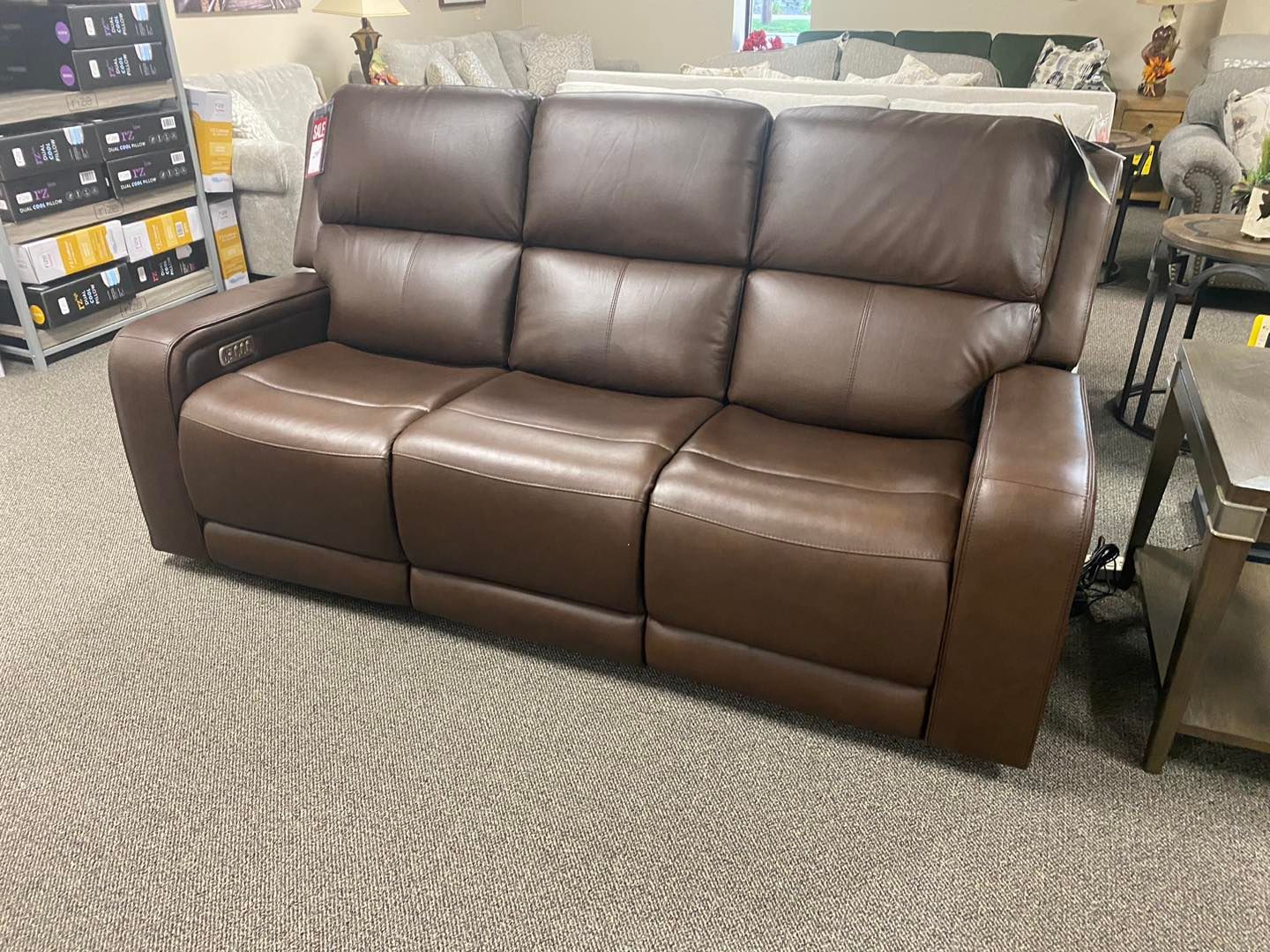 A brown leather recliner couch is sitting on a carpet in a living room.