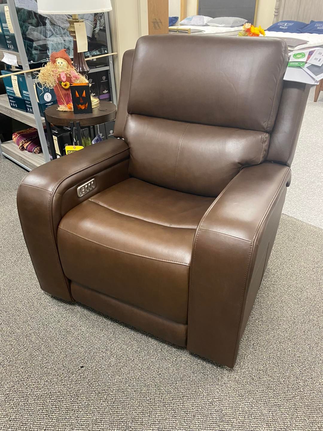 A brown leather recliner is sitting on a carpet in a room.