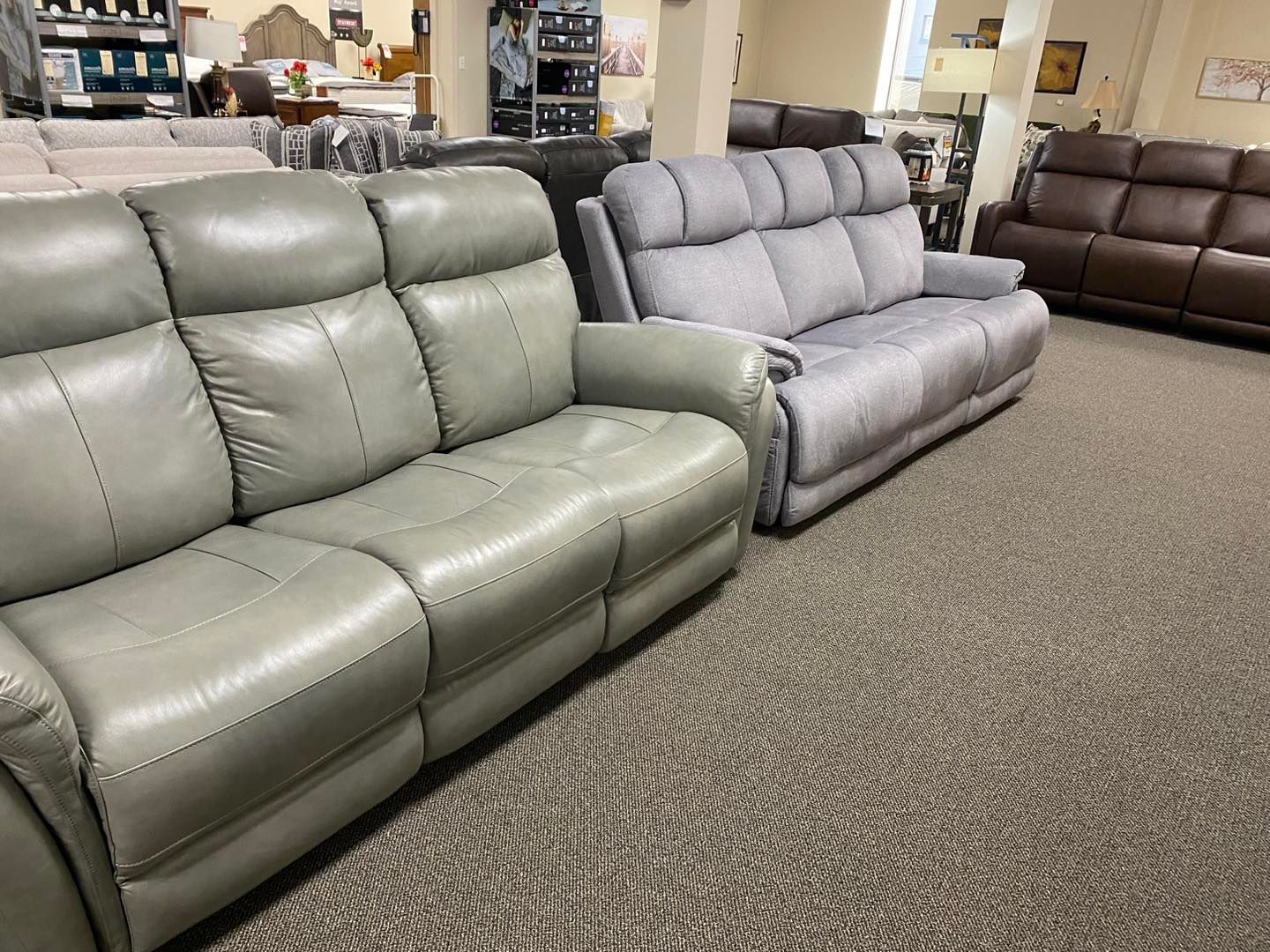 A row of leather couches are lined up in a living room.