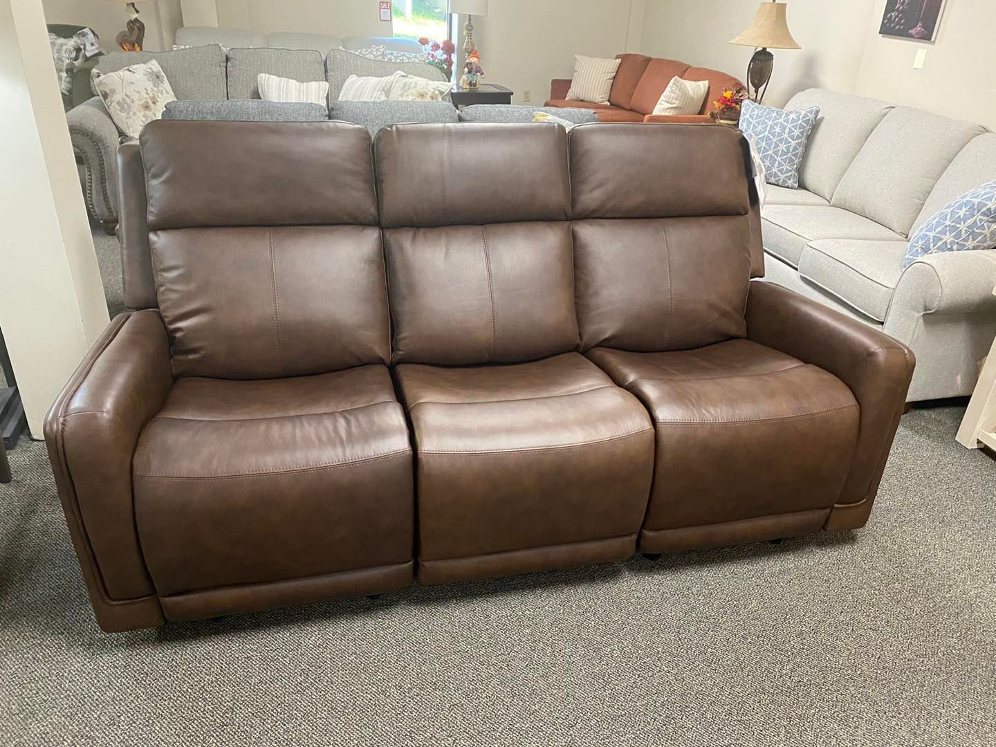 A brown leather recliner couch is sitting in a living room.