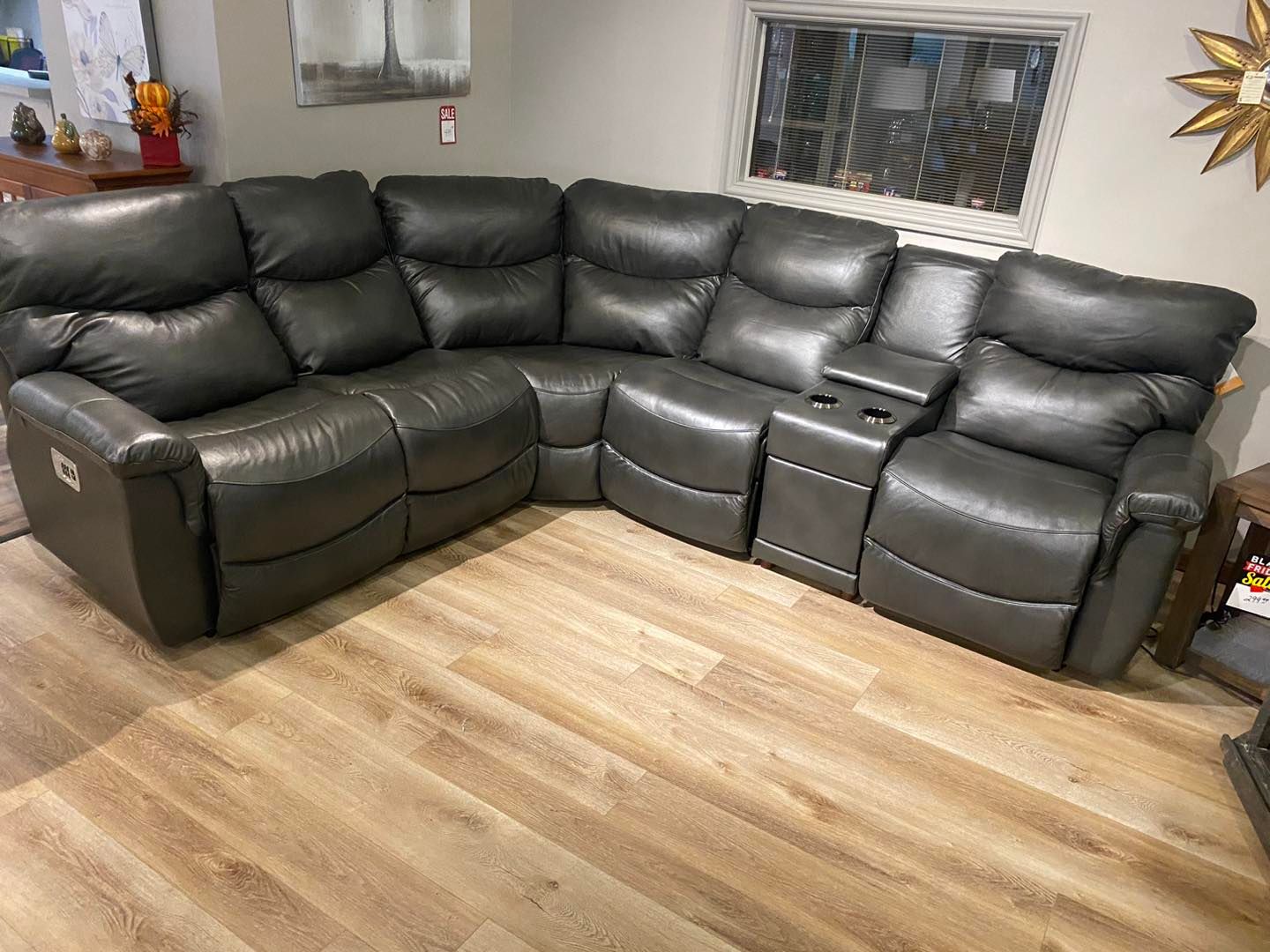 A gray leather sectional couch is sitting on a wooden floor in a living room.