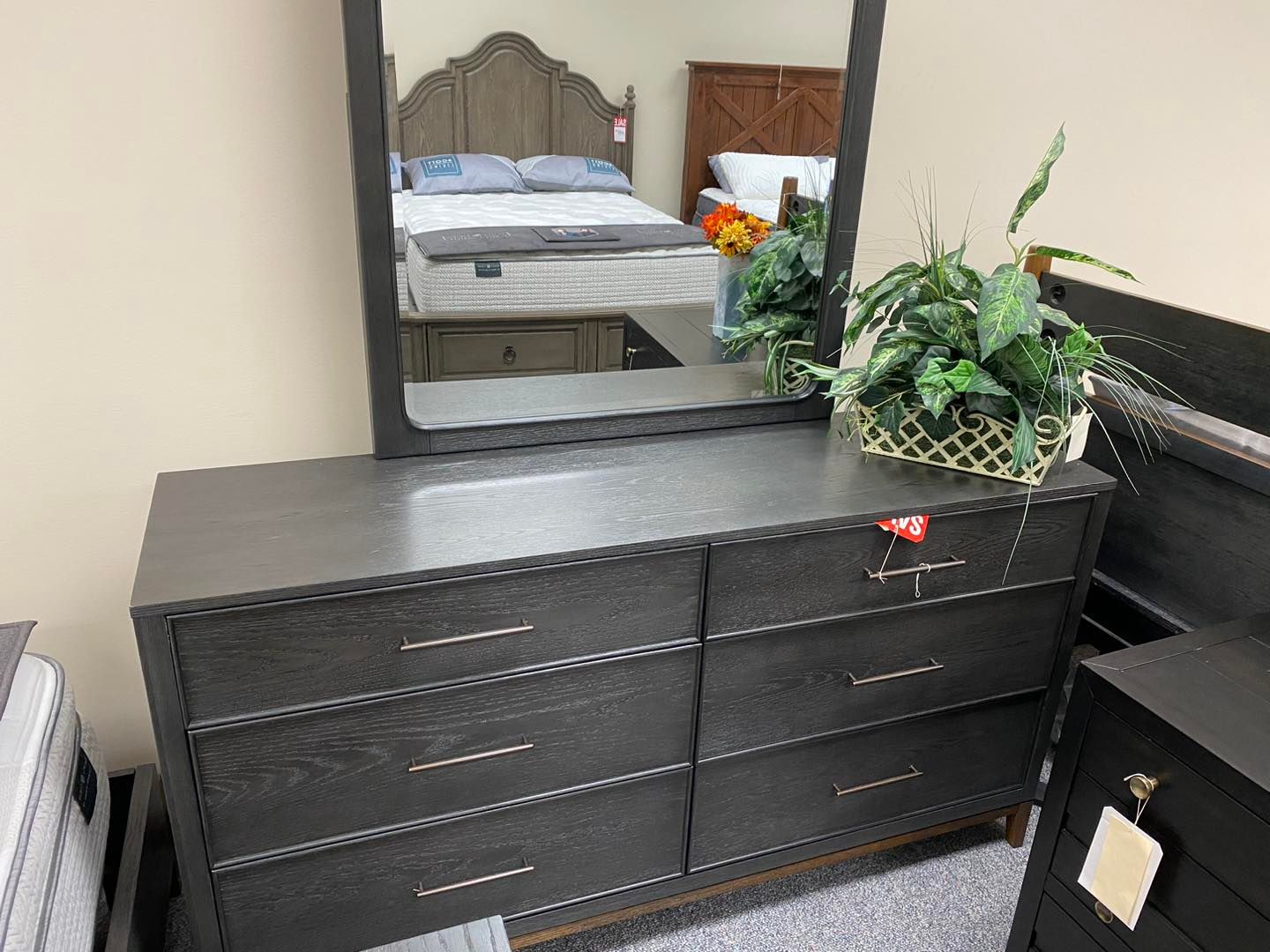 A bedroom with a dresser , mirror and bed.