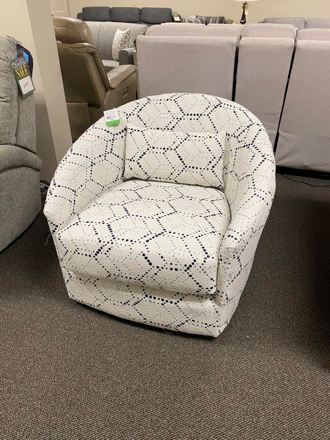 A white chair with a pattern on it is sitting on a carpet in a living room.